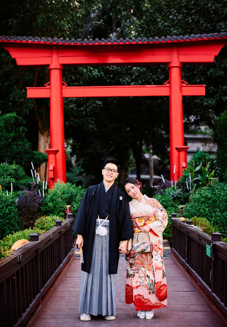 Yuna and Kai standing on a wooden bridge under a red gate