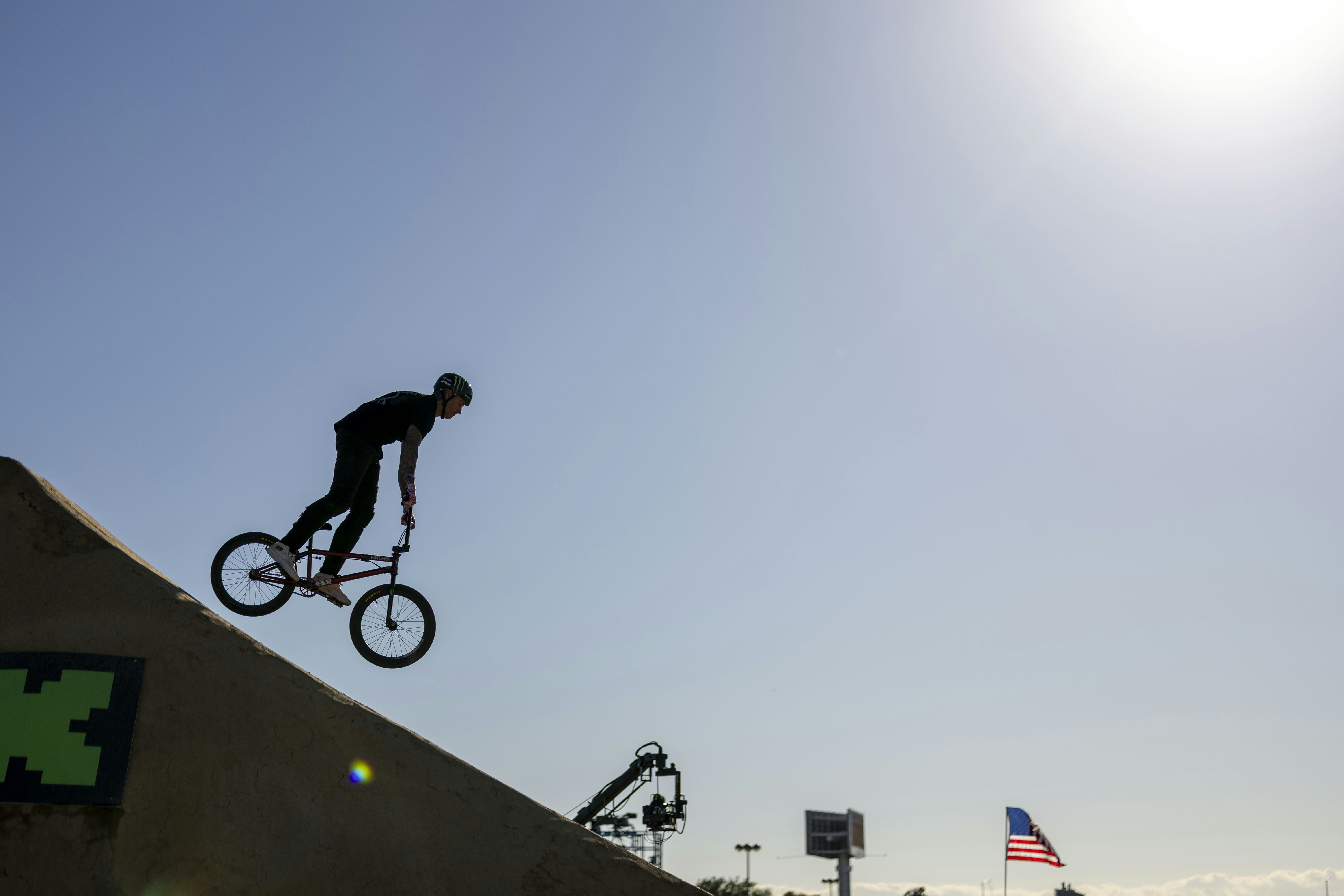 Seorang pengendara bmx bersiluet melompat dari tanjakan