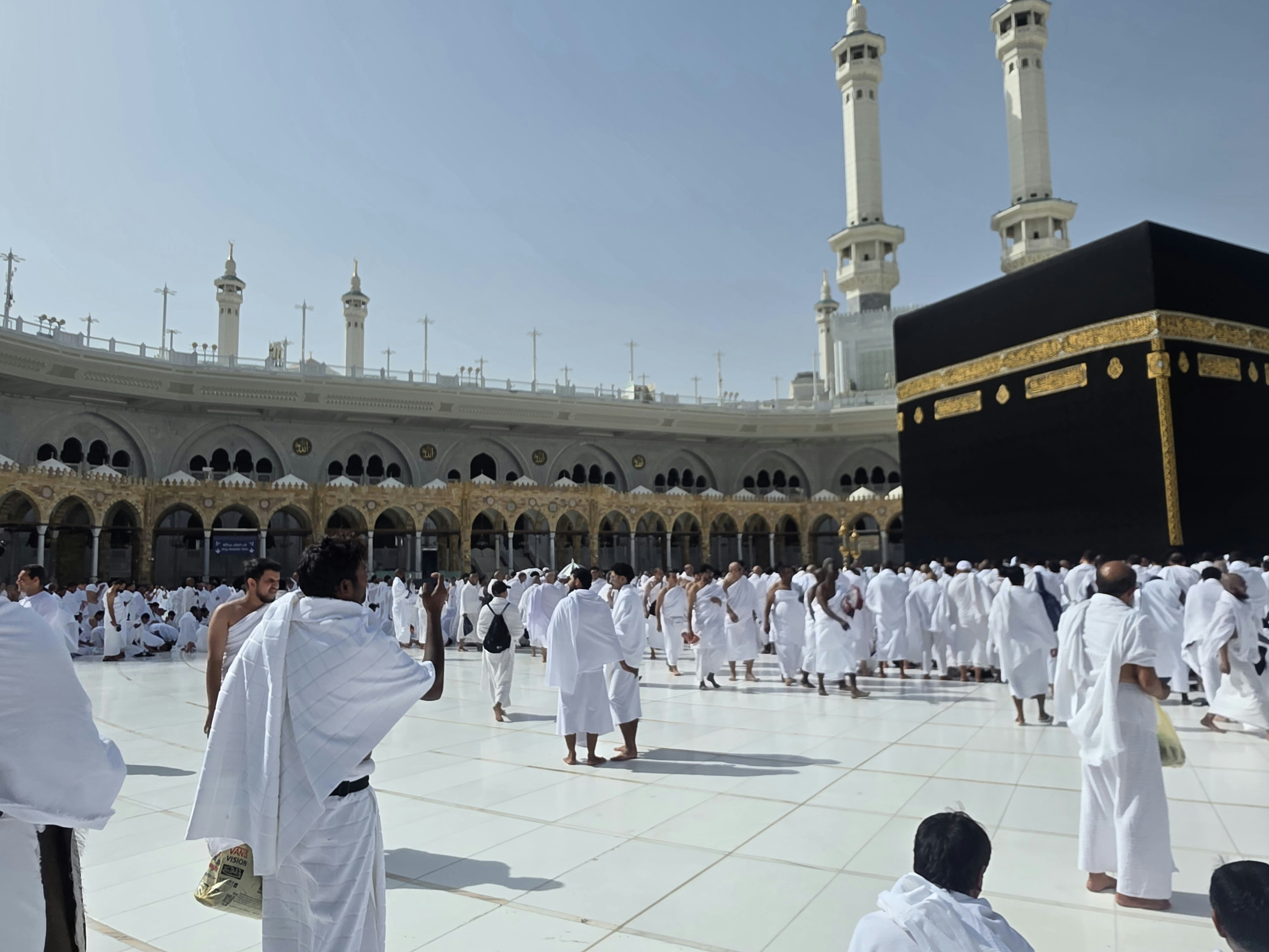 Pilgrims in white robes gather around the kaaba in mecca.