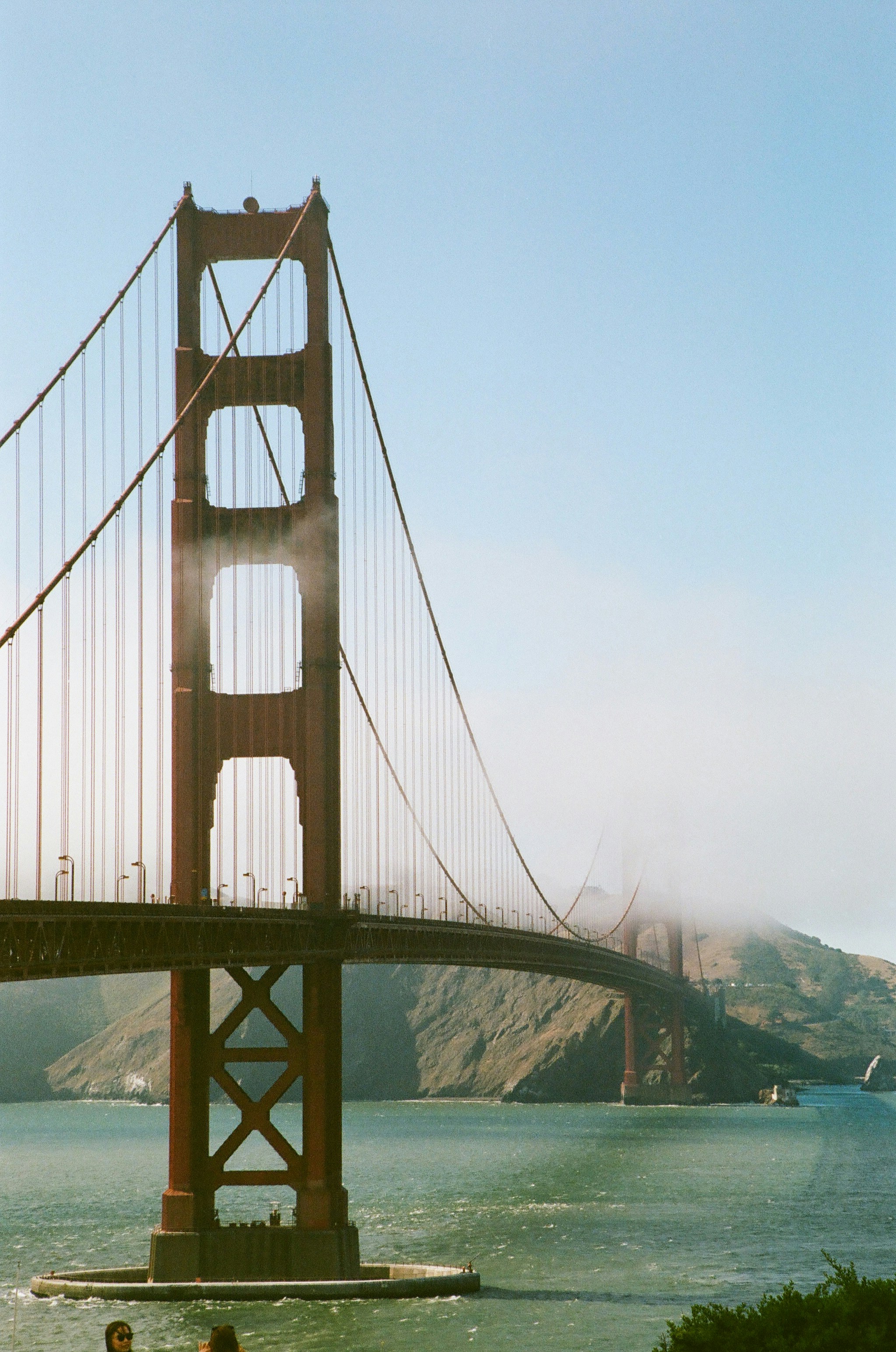 The golden gate bridge with fog rolling over the hills.