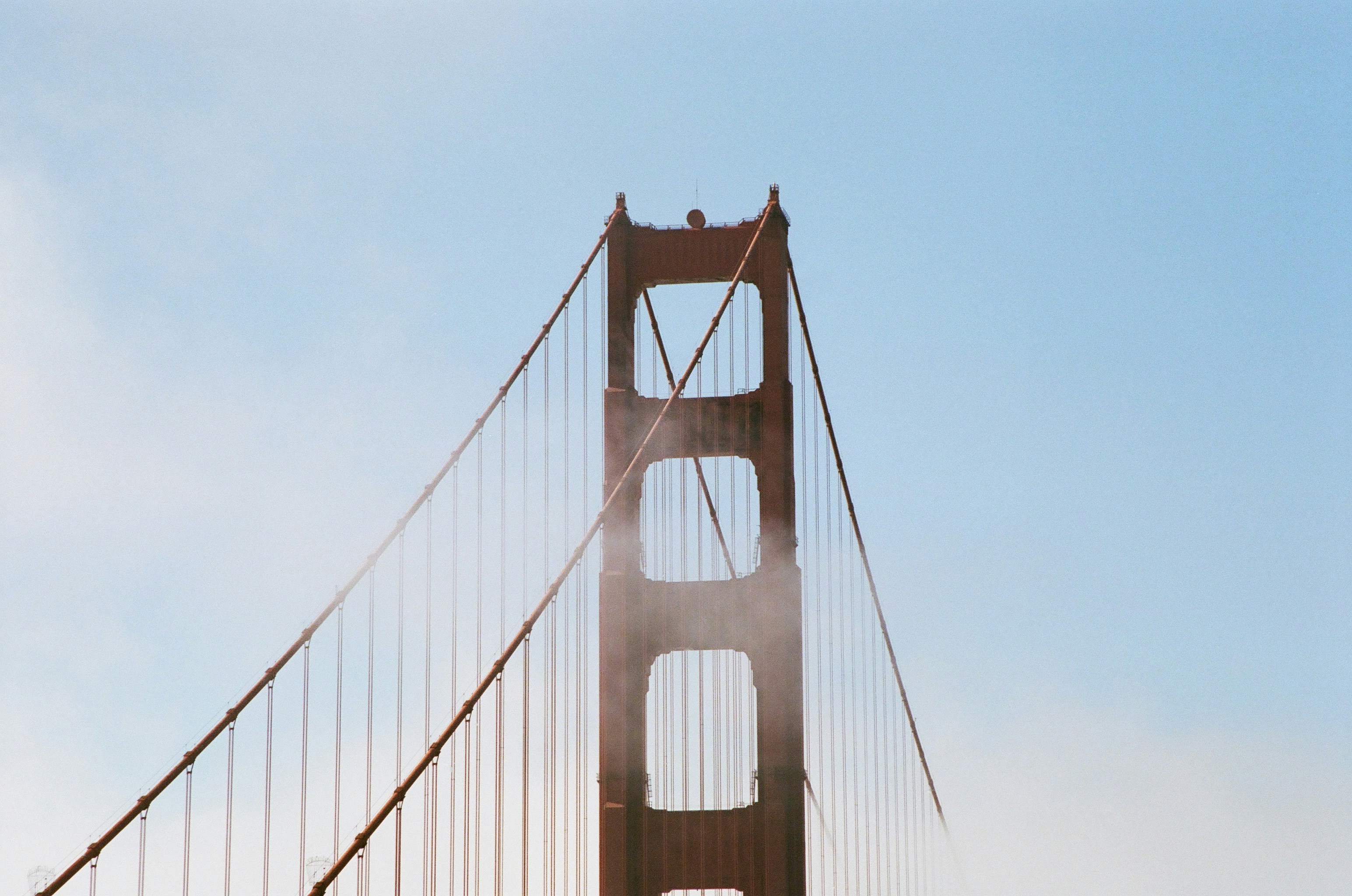 Golden gate bridge tower and cables in light fog.