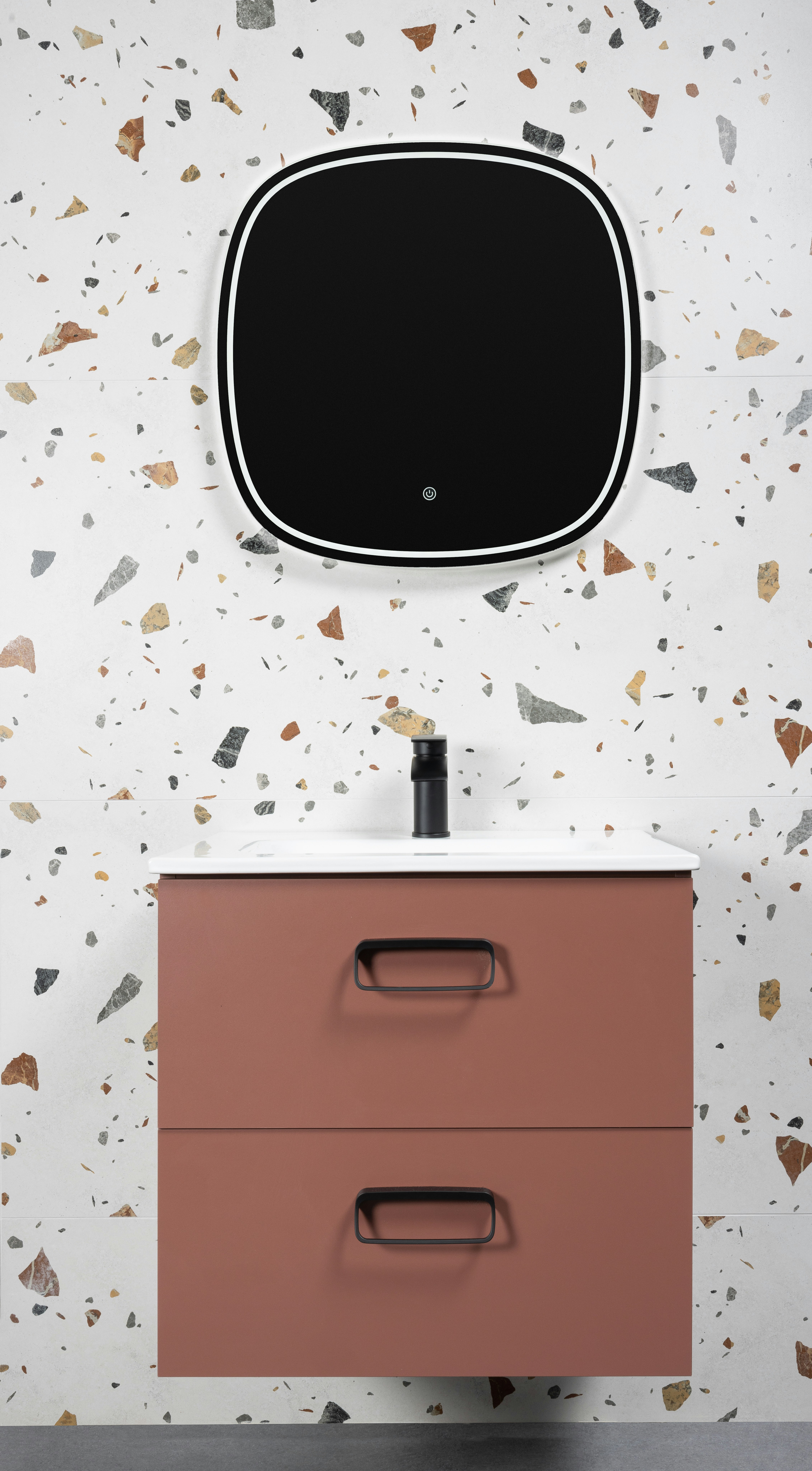 Tocador moderno de baño con espejo contra una pared de terrazo.