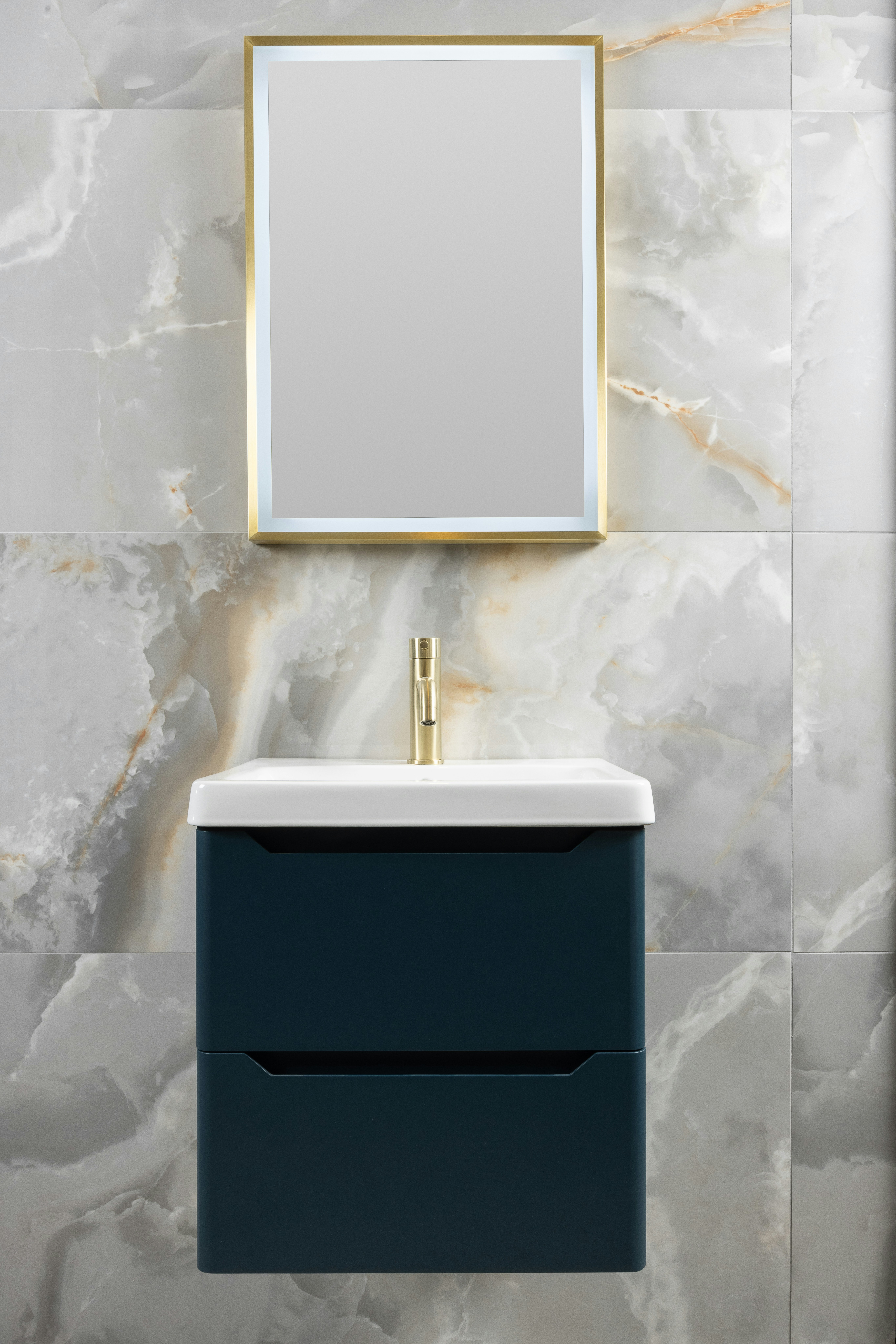 Tocador moderno de baño con detalles dorados y pared de baldosas de mármol.