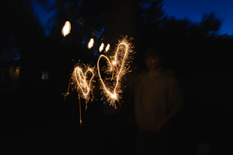 Two sparkling hearts drawn in the dark by a person.