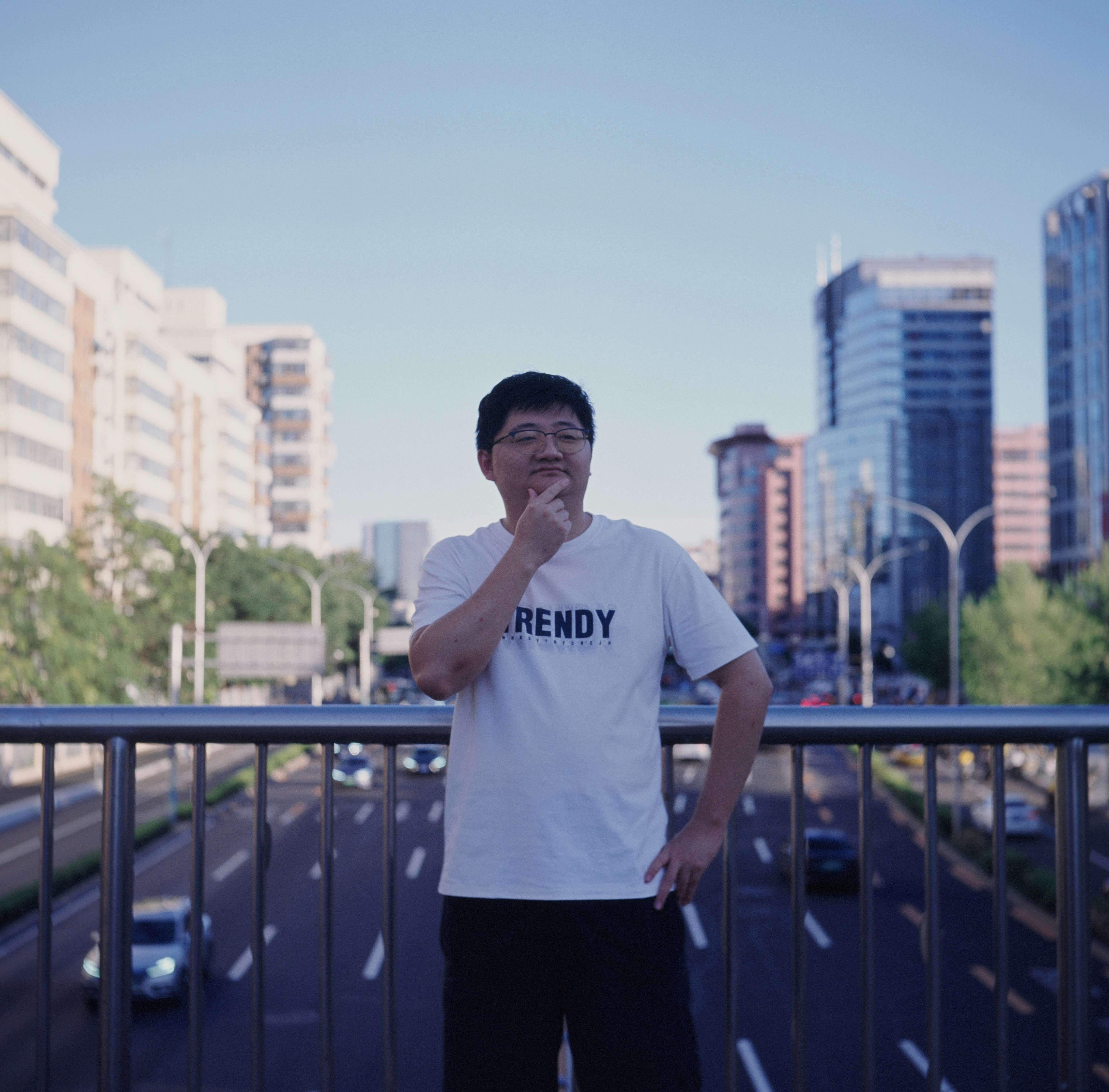 Thoughtful man on a city bridge overlooking traffic.