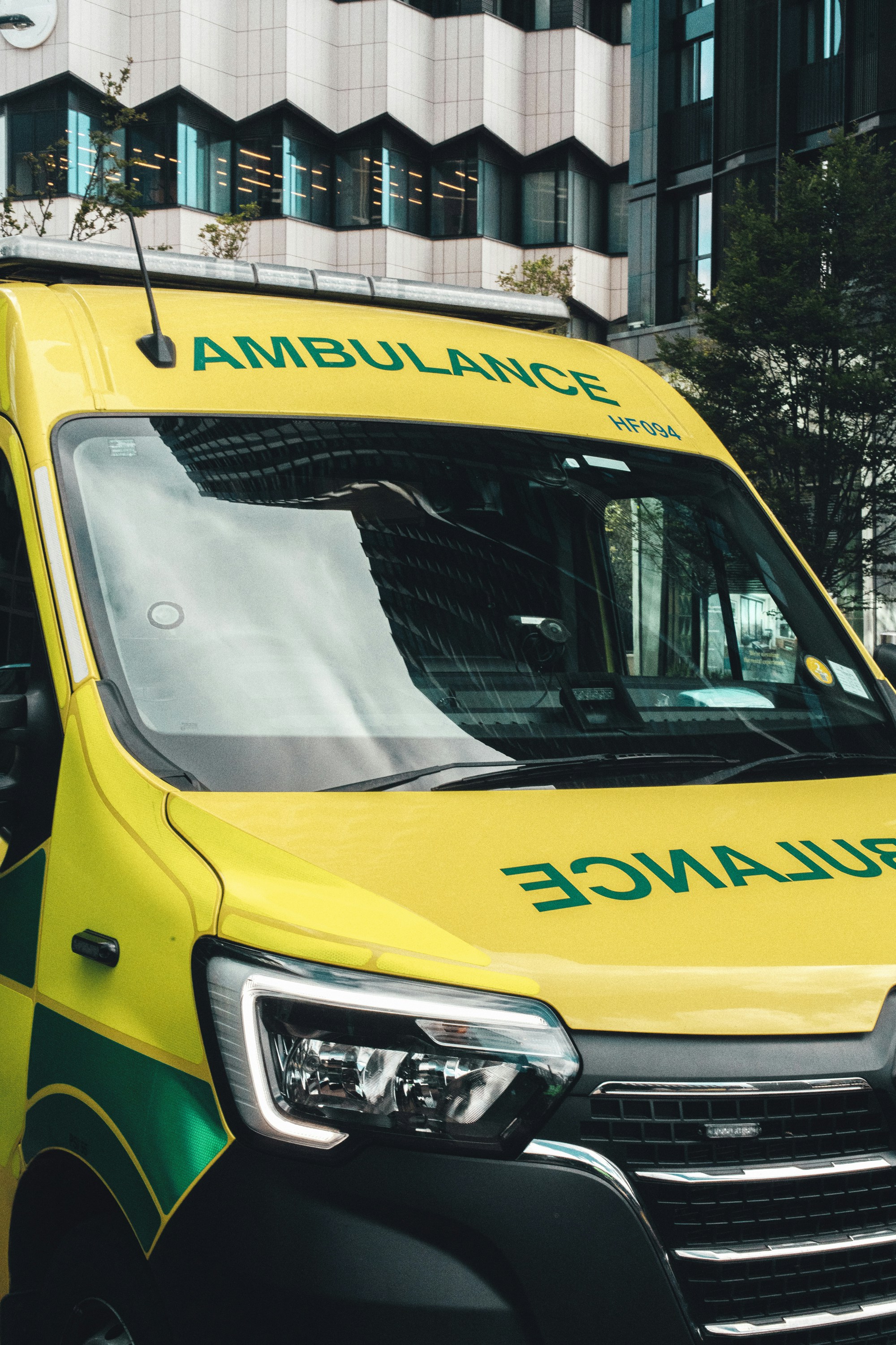 Yellow ambulance parked in front of a modern building