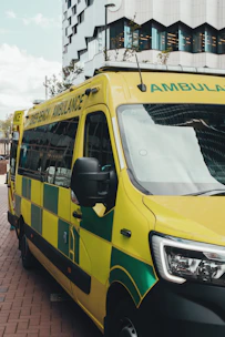 A yellow and green ambulance parked on a city street