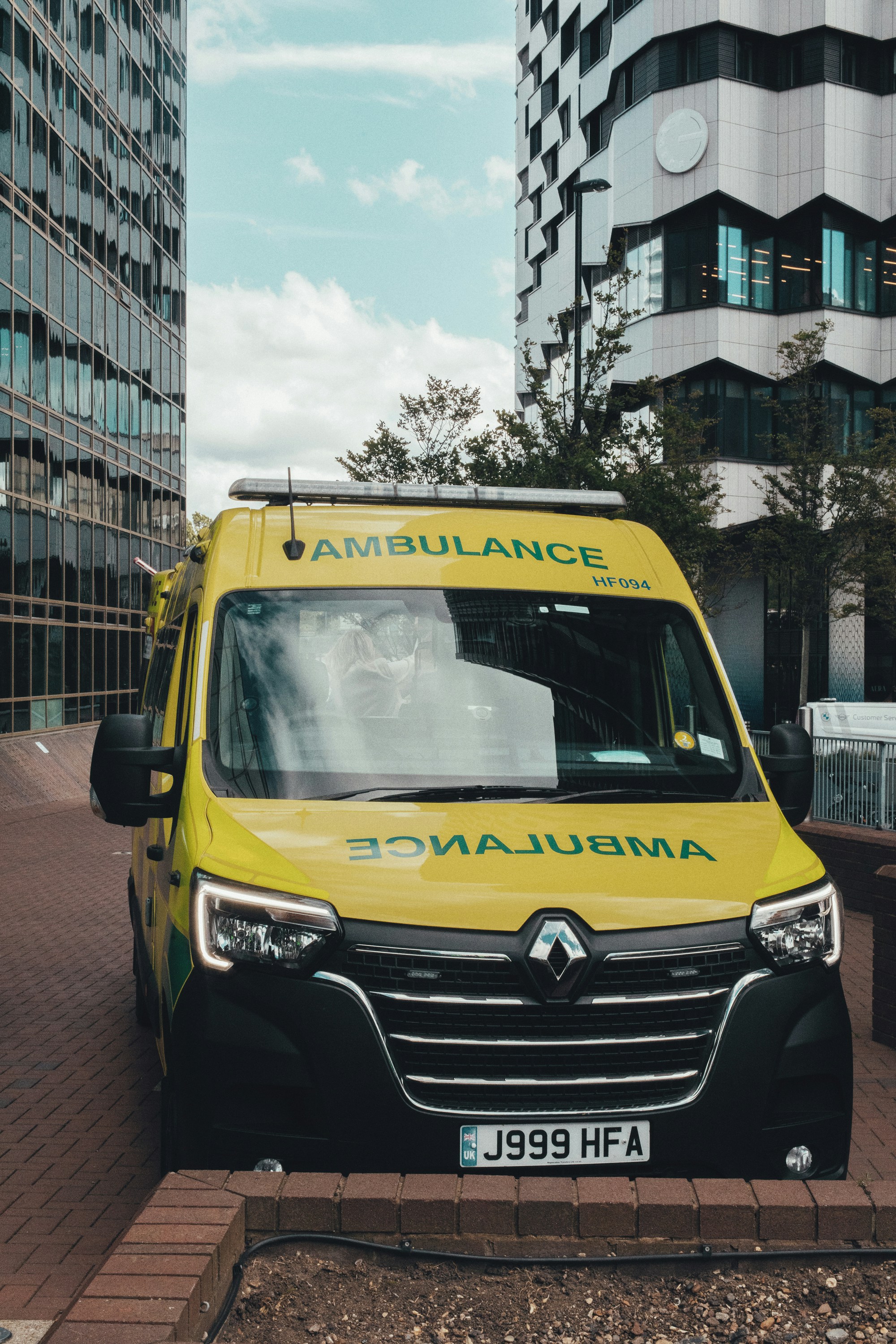A yellow ambulance parked on a street between modern buildings