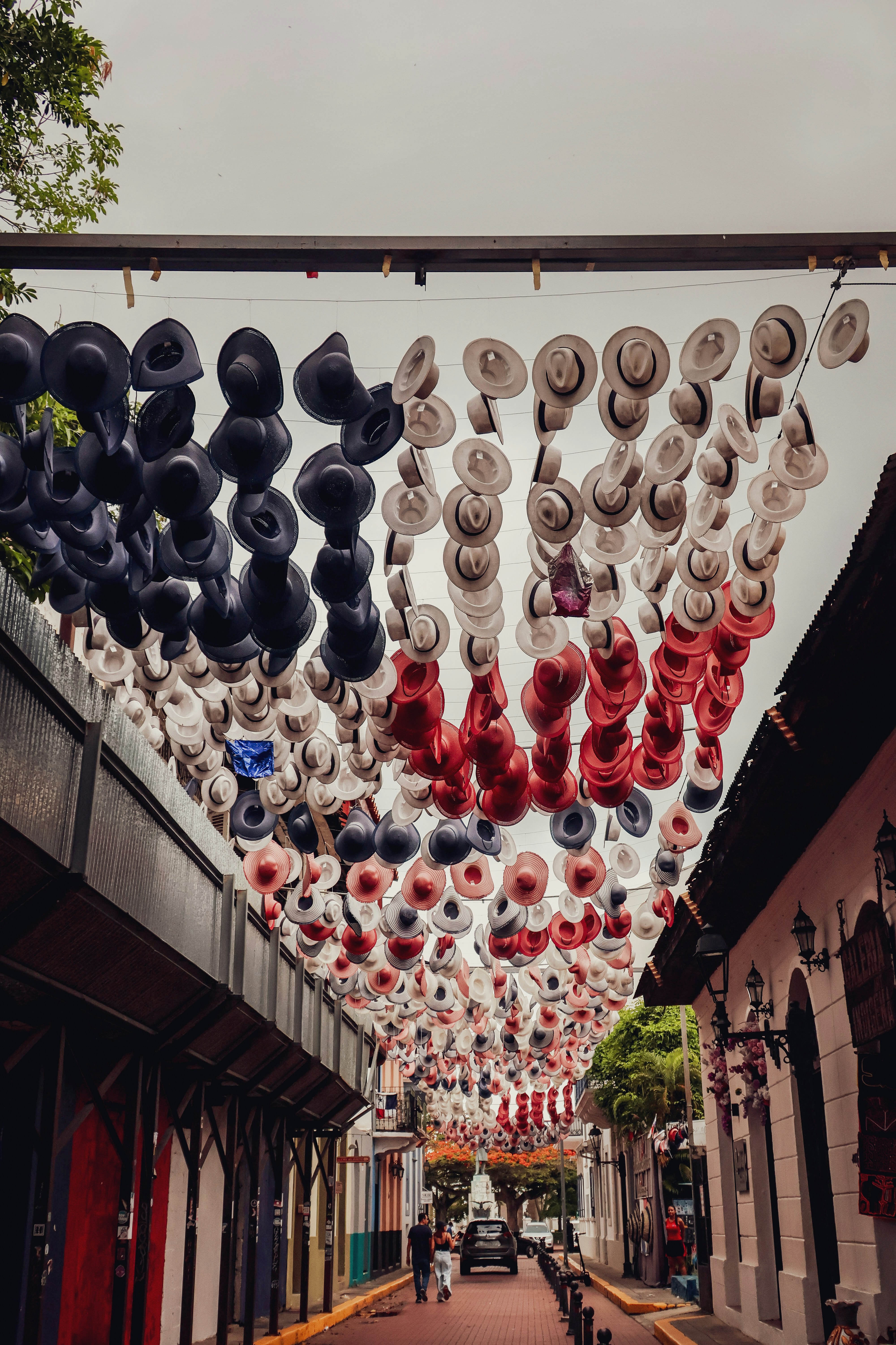 Street decorated with suspended black, white, and red hats.
