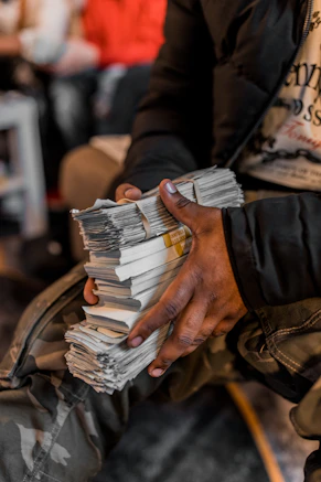 Hands holding a thick stack of dollar bills