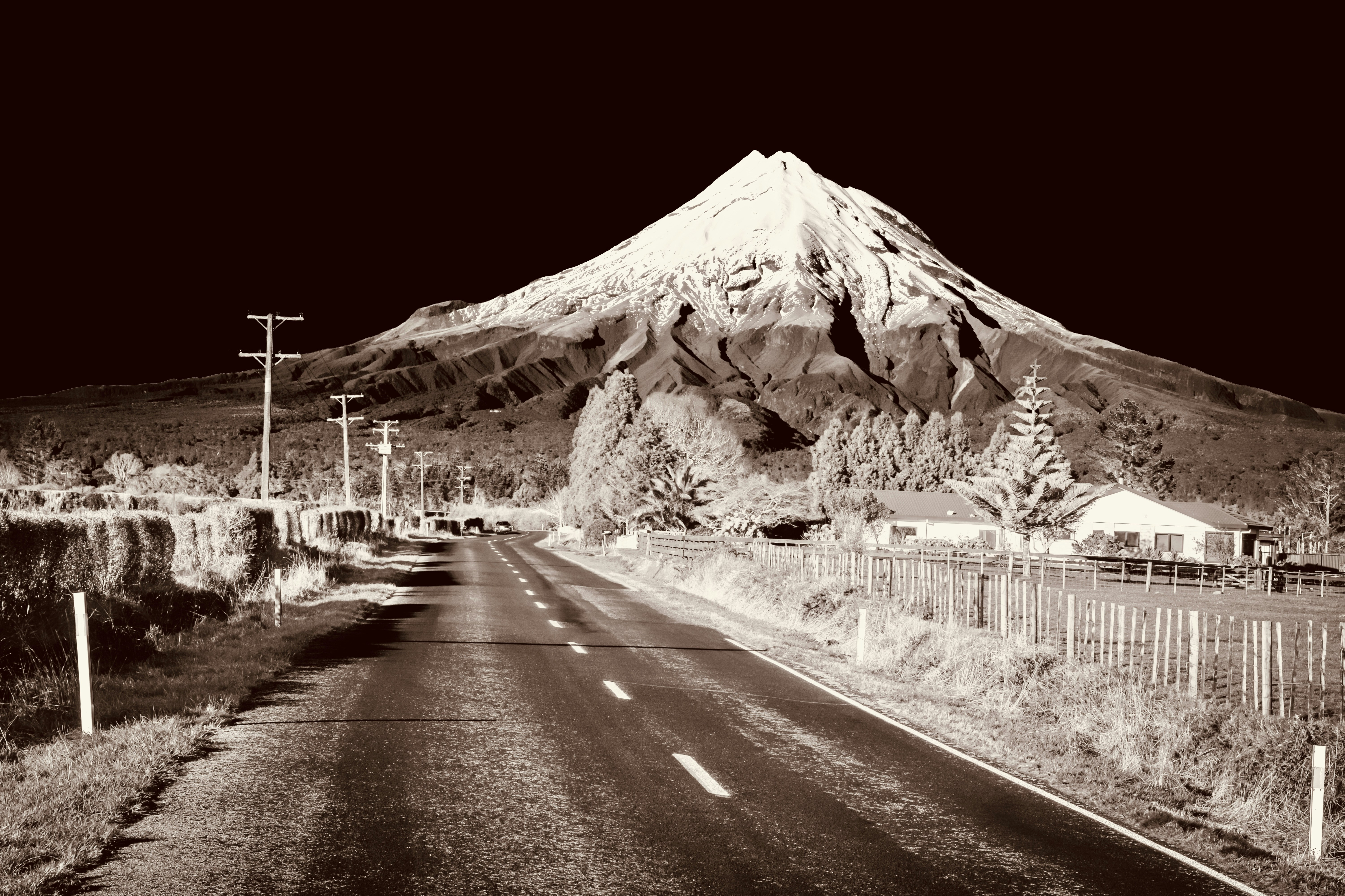 Infrared view of a snow-capped mountain and rural road.