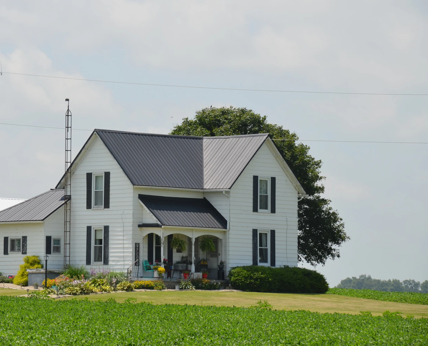 Classic white farmhouse with covered porch on a wide green lawn