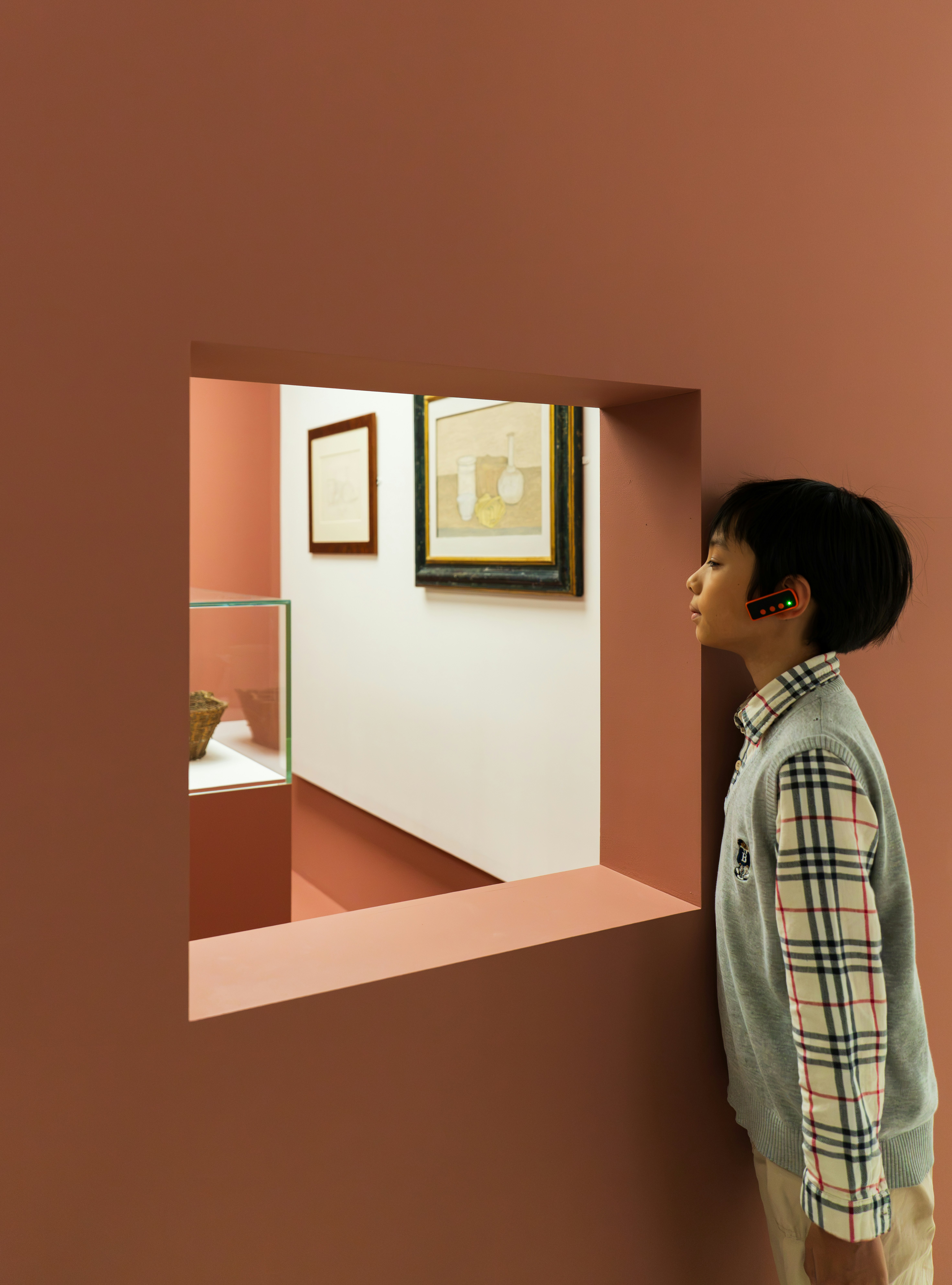 Boy looking through terracotta wall at artwork