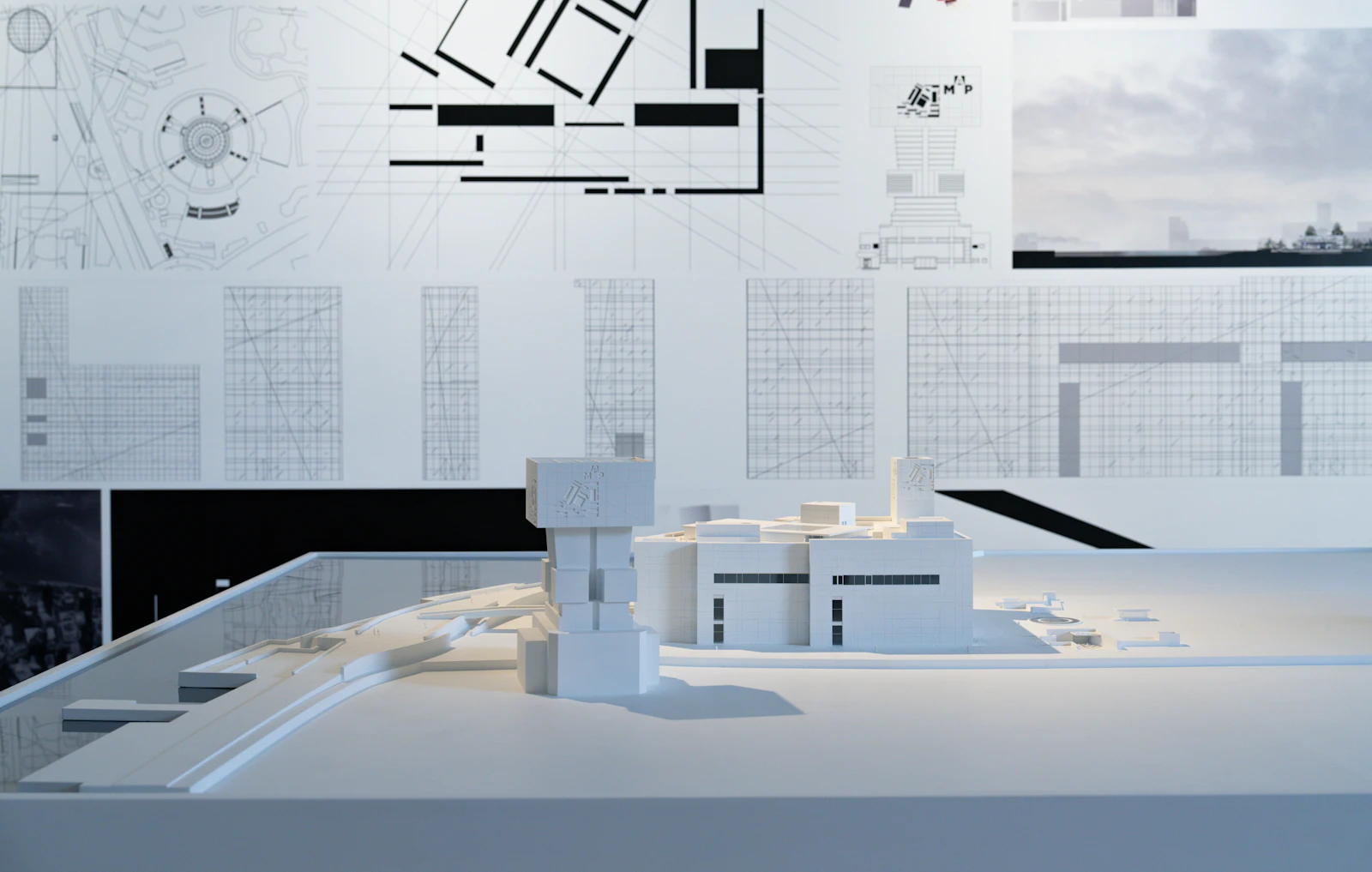 Maquete de um projeto arquitetônico exposta ao lado dos desenhos técnicos.