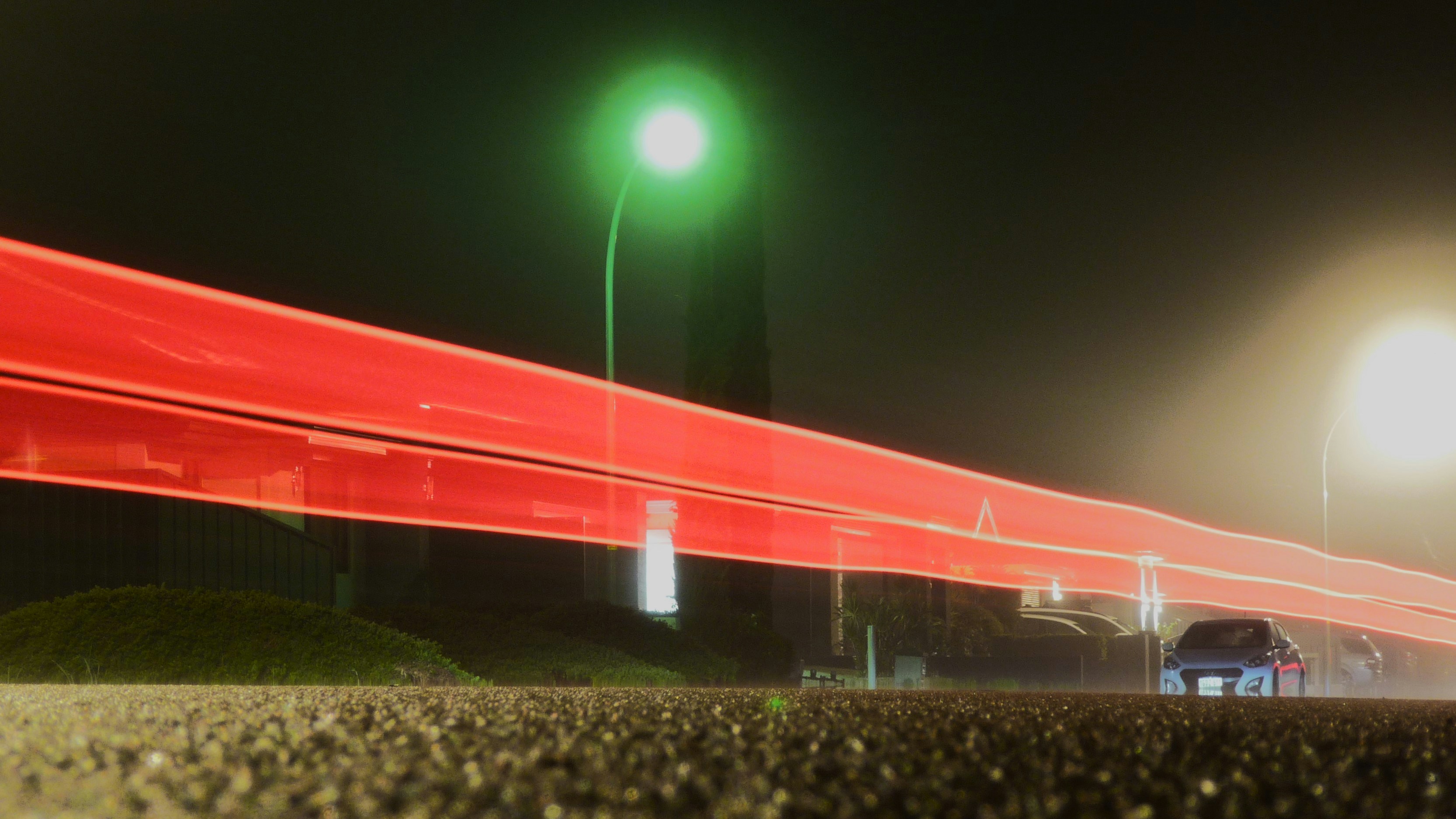 Long red light trails on a dark road at night.