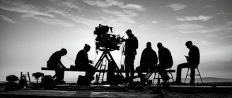 Film crew with large camera under a cloudy sky