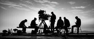 Film crew with large camera under a cloudy sky