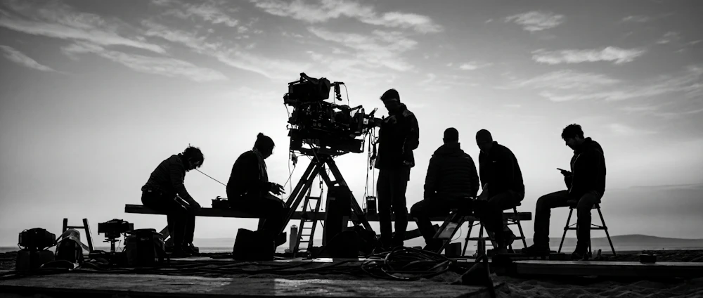 Film crew silhouetted on set at sunset