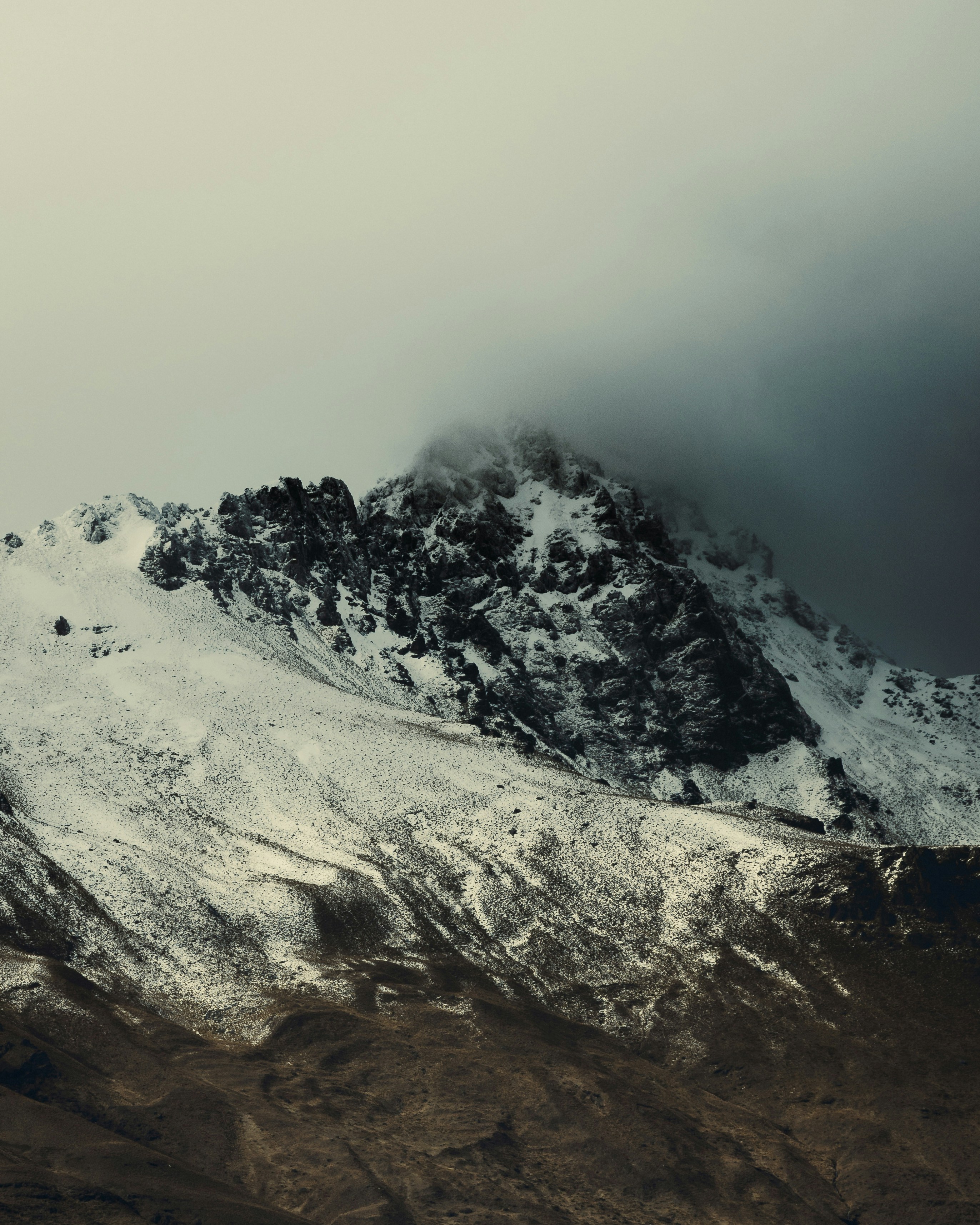 Zerklüfteter Berggipfel, bedeckt mit Schnee und Nebel