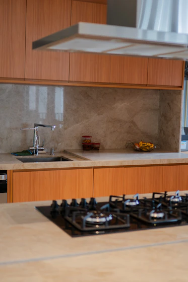 Modern kitchen with wooden cabinets, marble backsplash, and gas stovetop