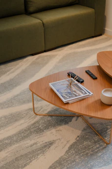 Two remote controls resting on a wooden coffee table beside a sofa