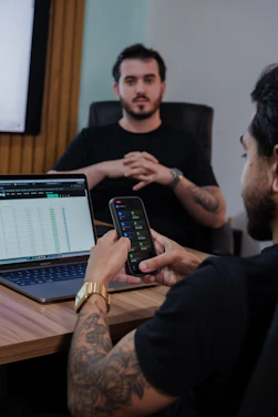 Man uses smartphone while colleague watches in an office