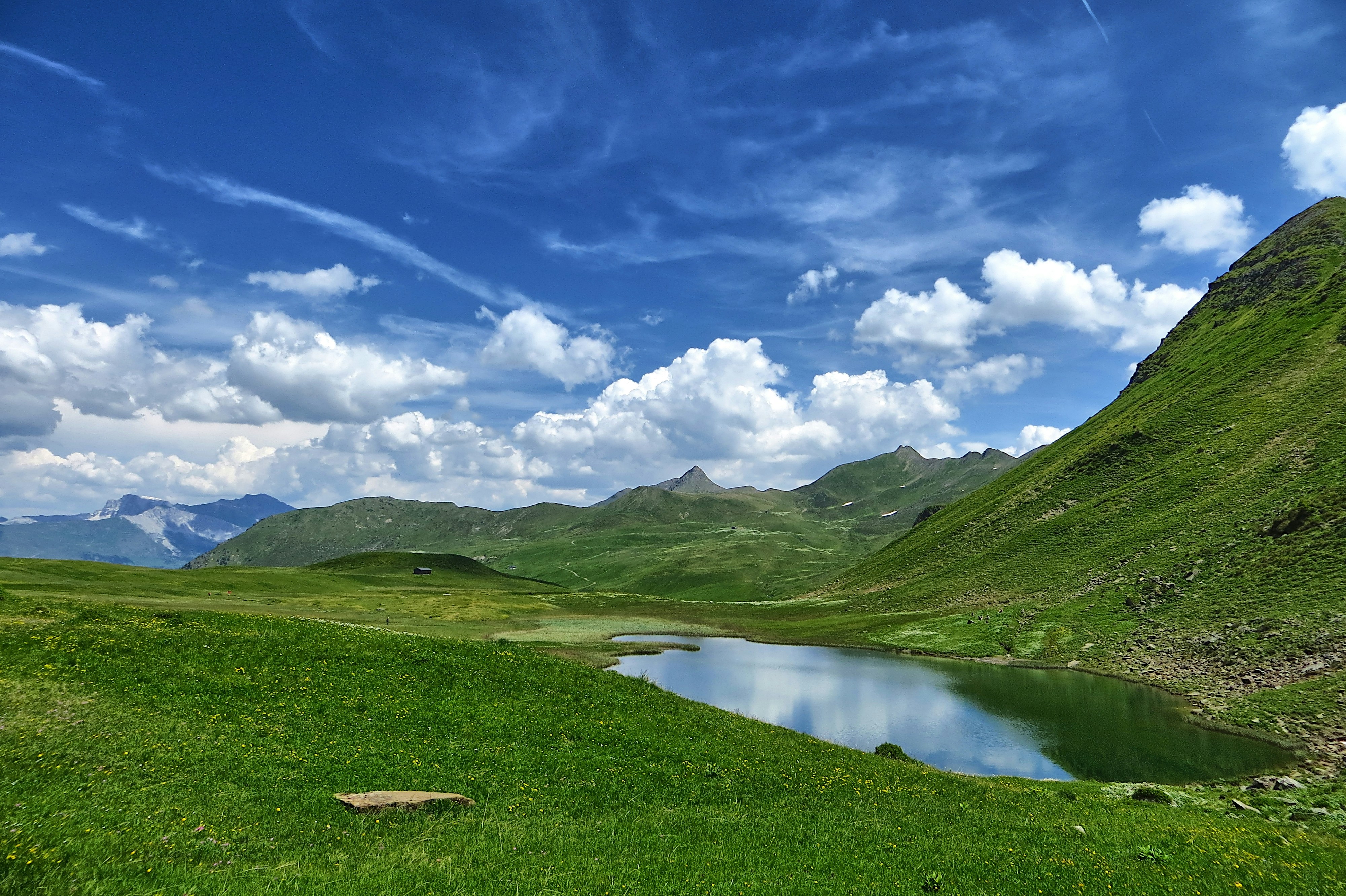 Colinas verdes y un lago tranquilo bajo un cielo azul.