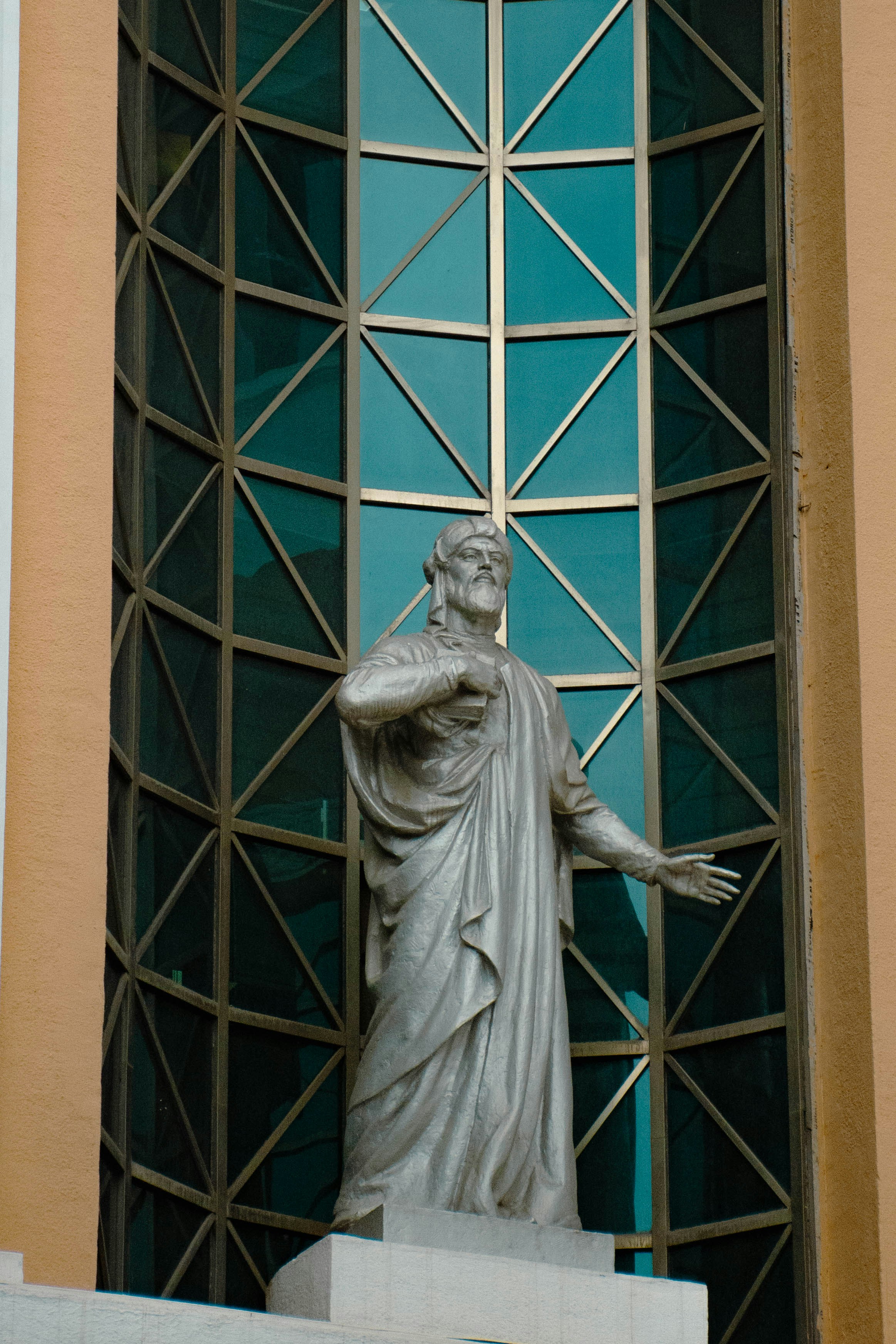 Stone statue of a bearded man before geometric windows