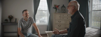 Two men conversing in a sunlit room