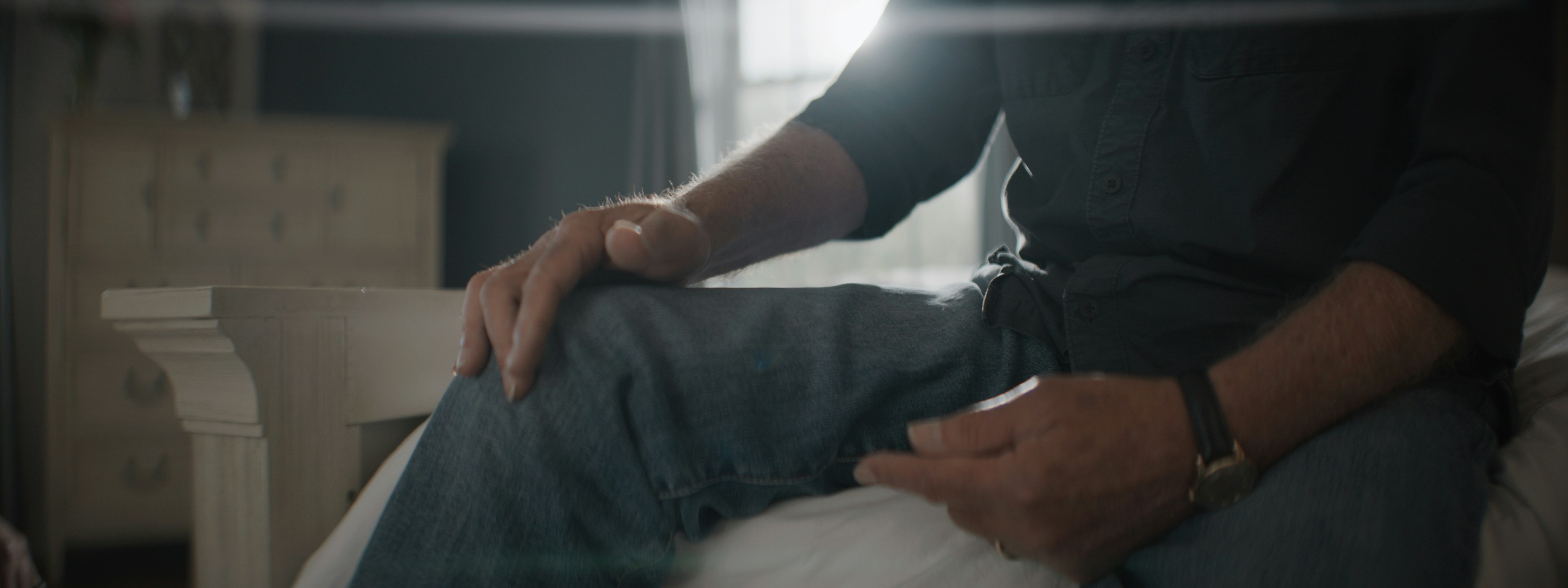 person holding pills and glass of water at bedside