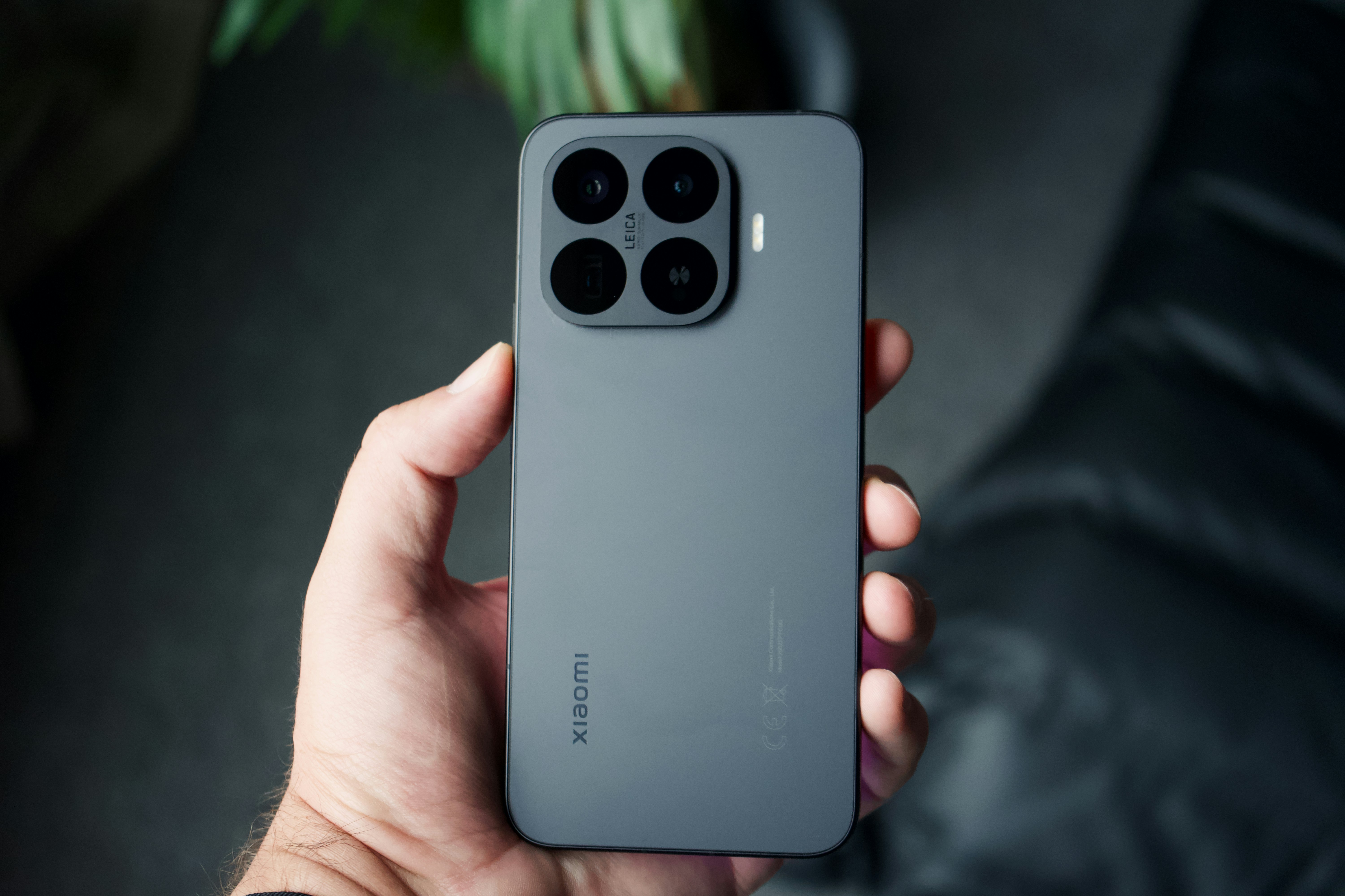 A hand holding a dark smartphone with four cameras.