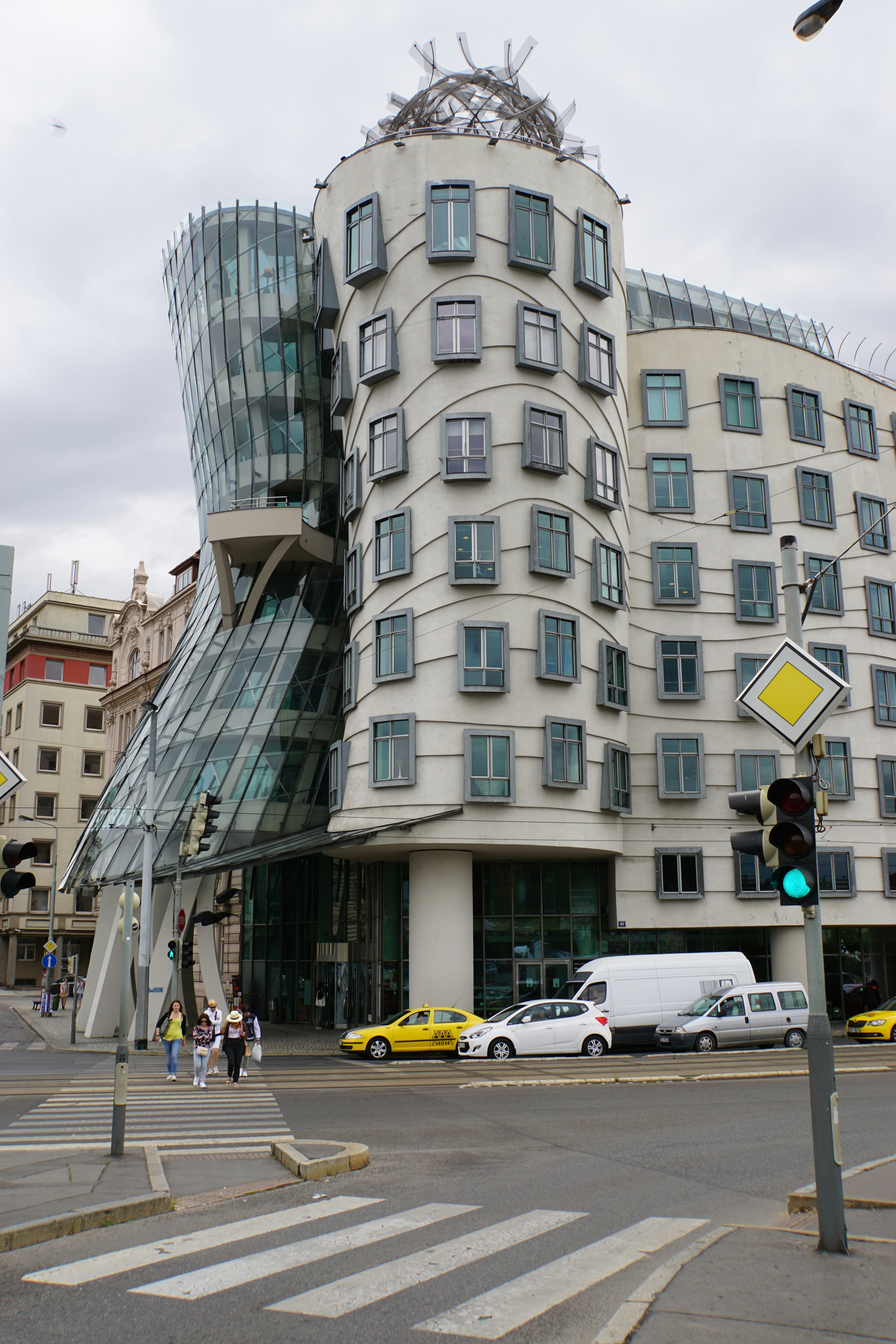 Iconic dancing house building on a city street with cars
