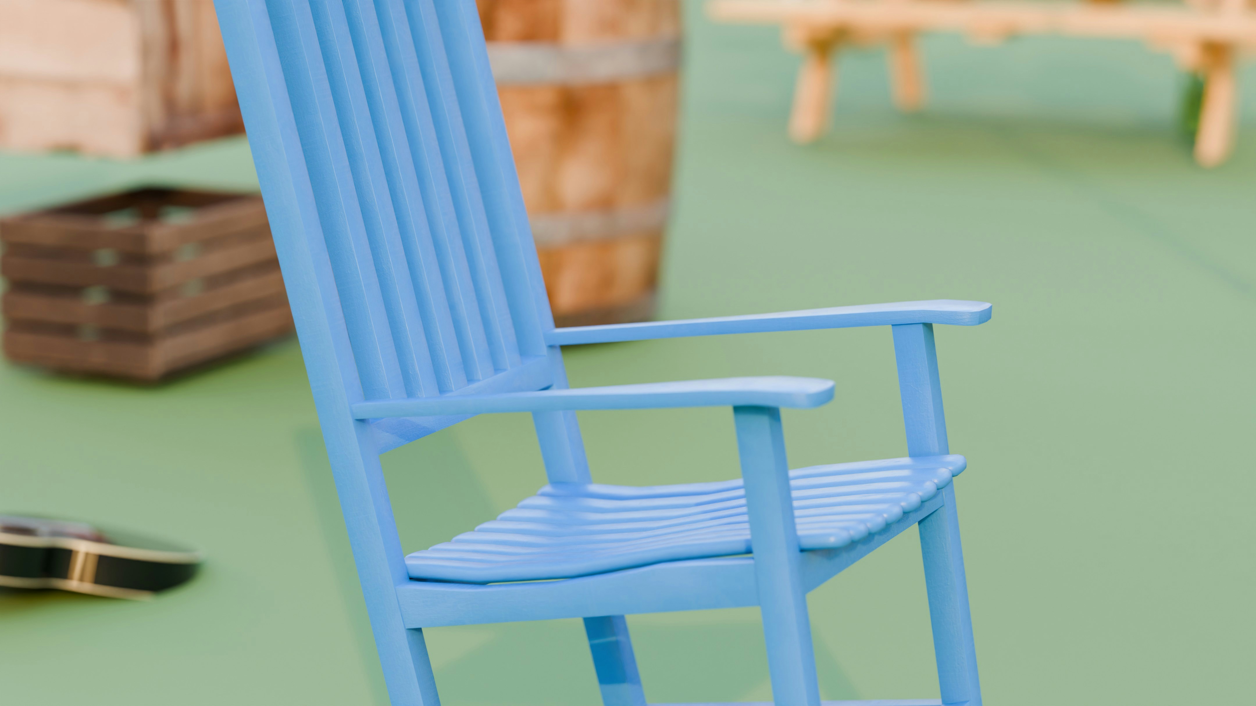 Blue wooden rocking chair on a green floor.