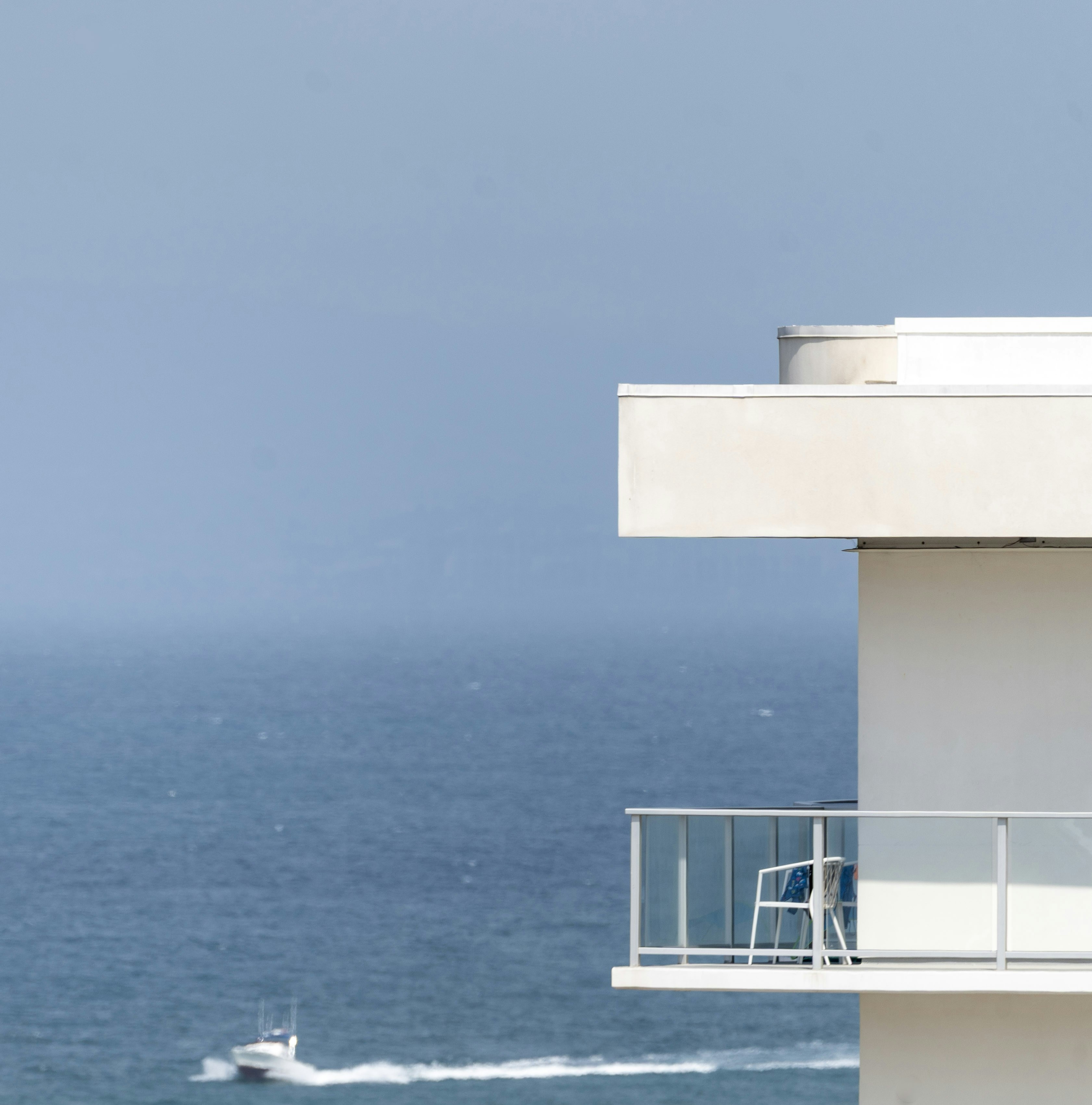Modern balcony overlooking a blue ocean with a boat.