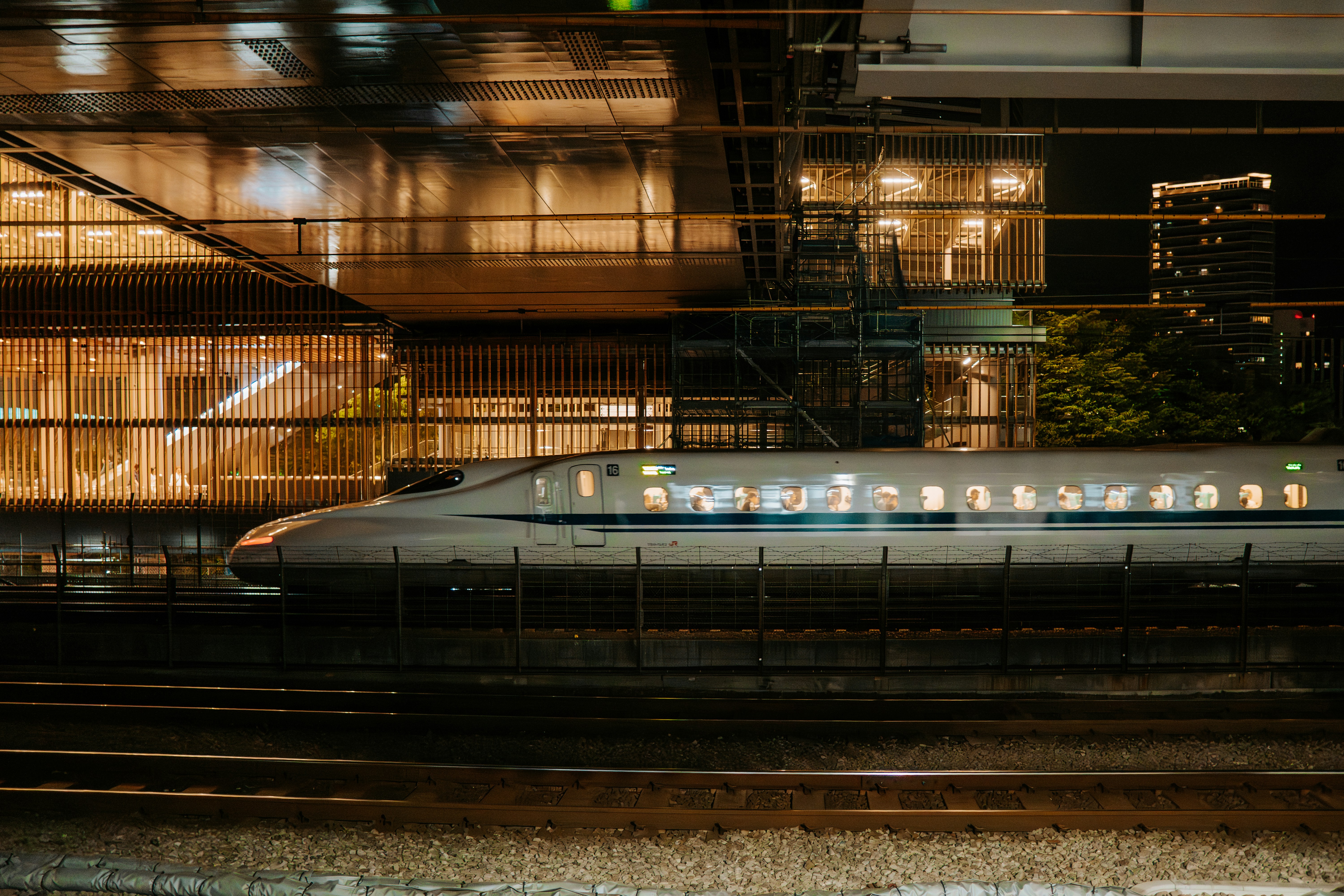 夜間に照明された建物の前を高速列車が通過する。