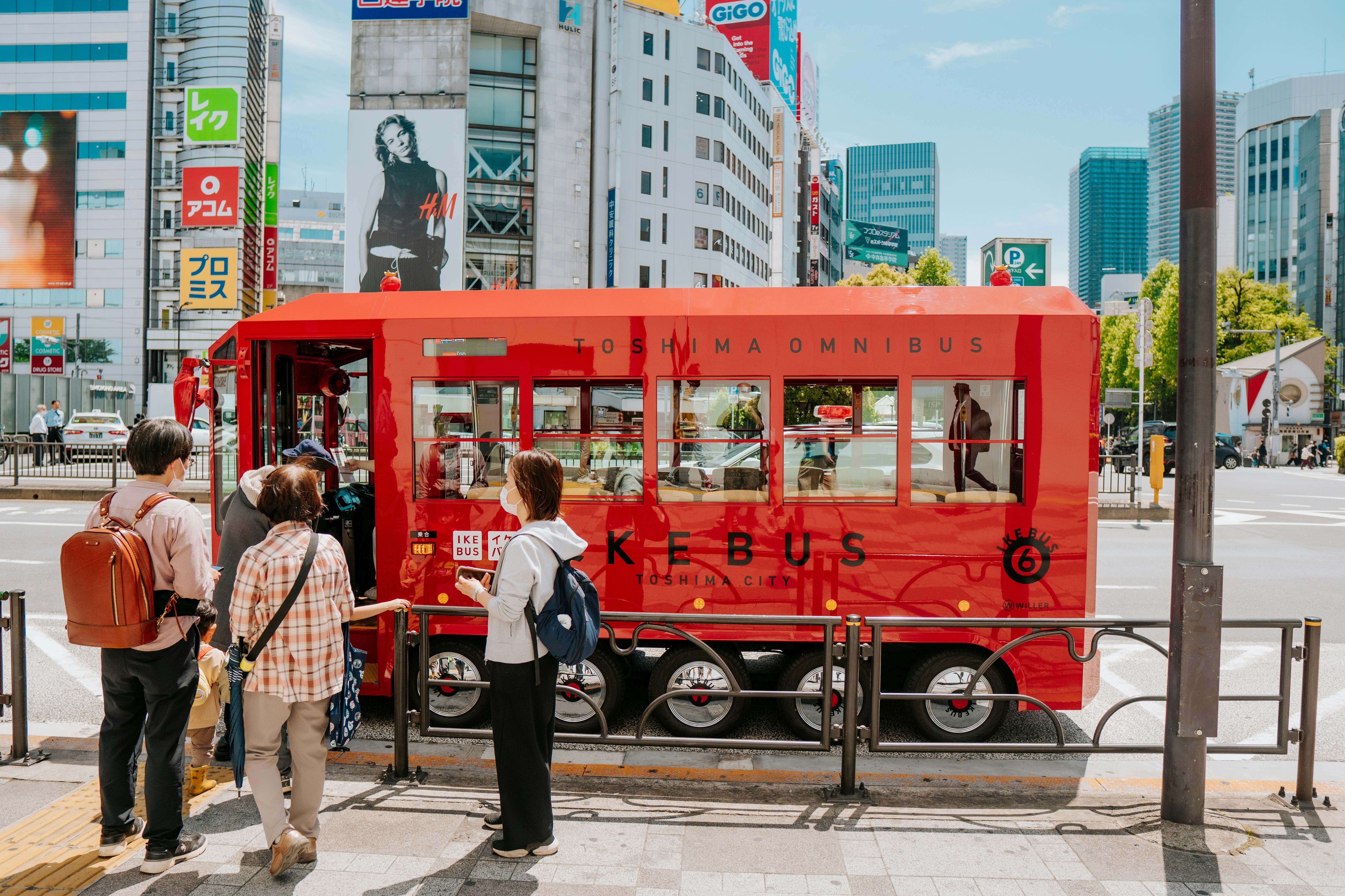 日差しの良い都市の通りに人が多い赤いバス型のキオスク。