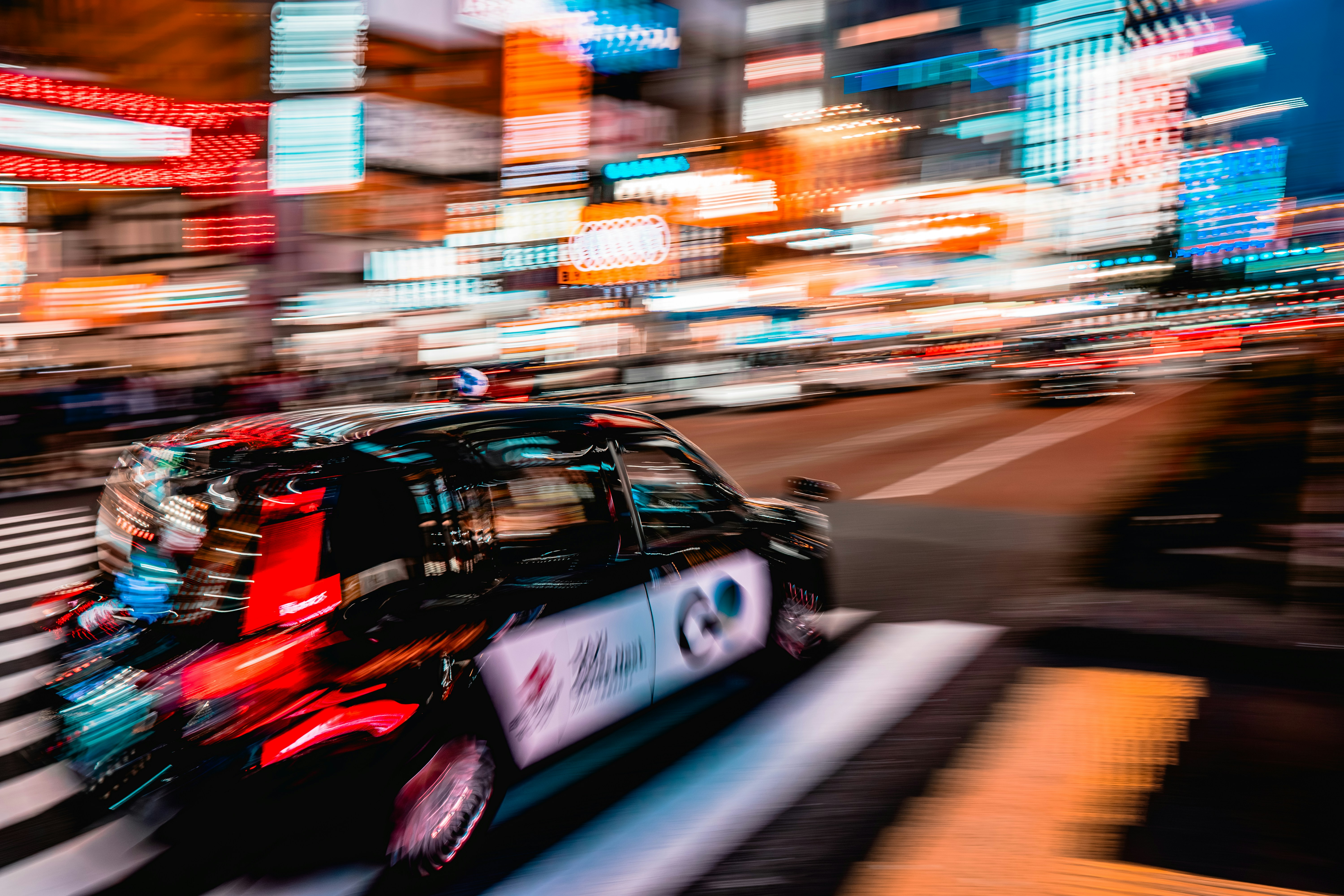 ぼやけたタクシーが夜の活気ある街を猛スピードで駆け抜ける。