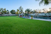 Spacious green lawn and swimming pool with lounge chairs