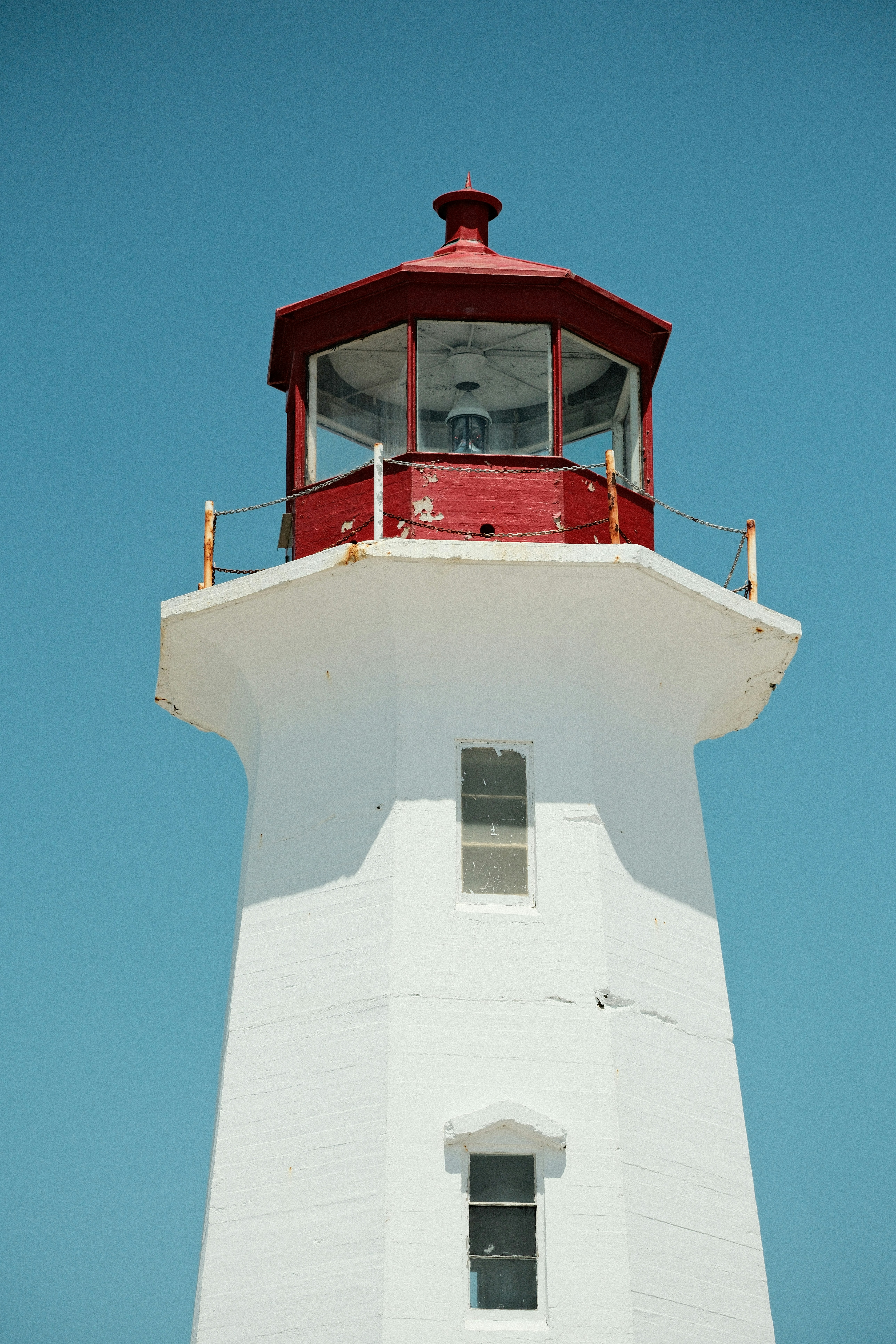 White lighthouse with a red top under clear blue sky.