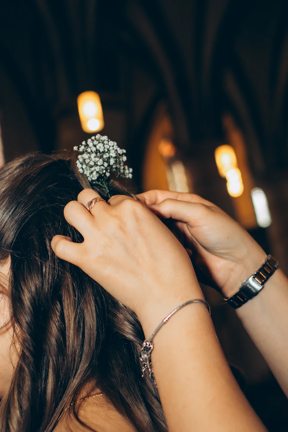 Mains posant une petite fleur blanche dans une coiffure