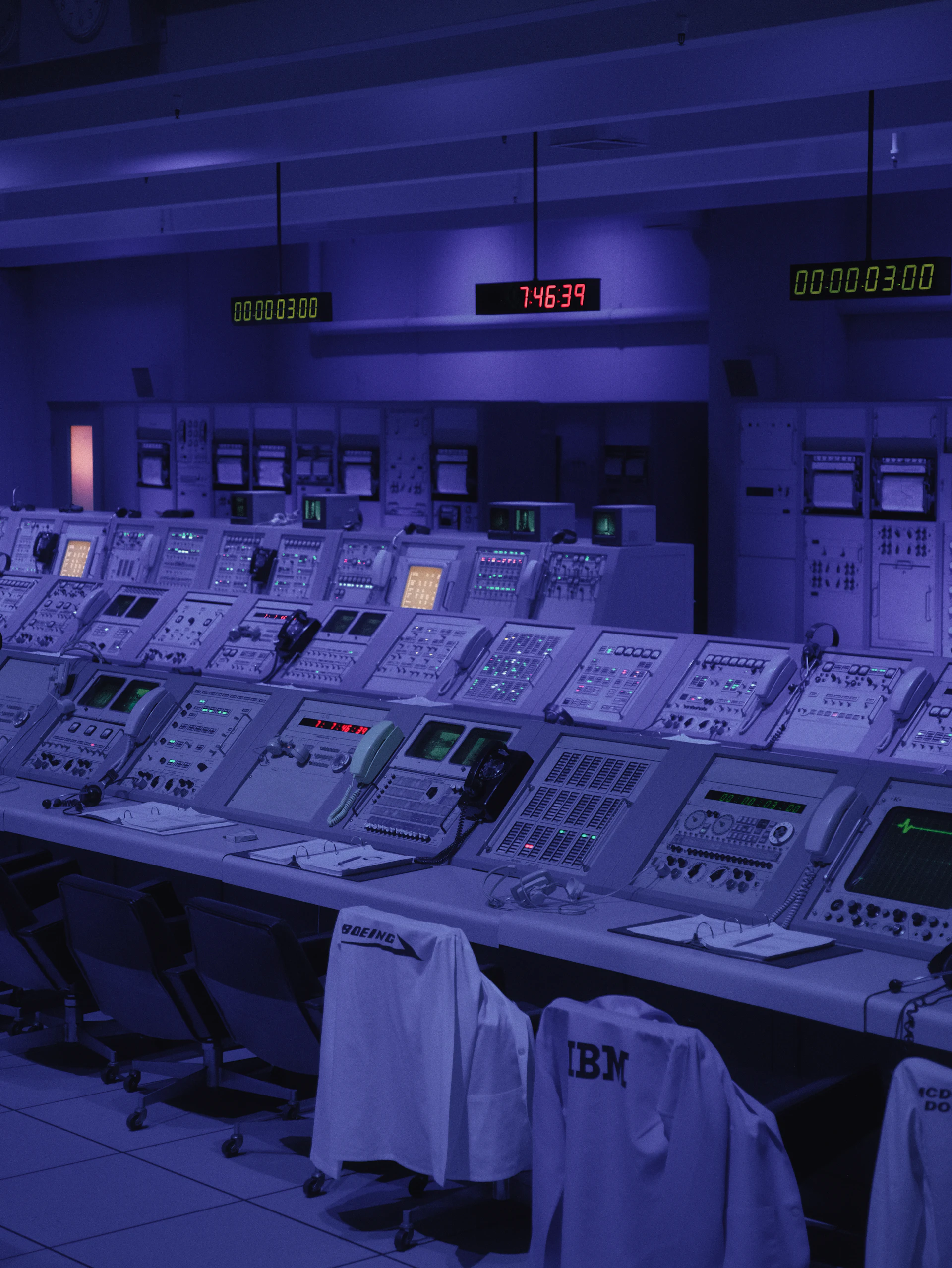 Blue lit mission control room with rows of consoles.