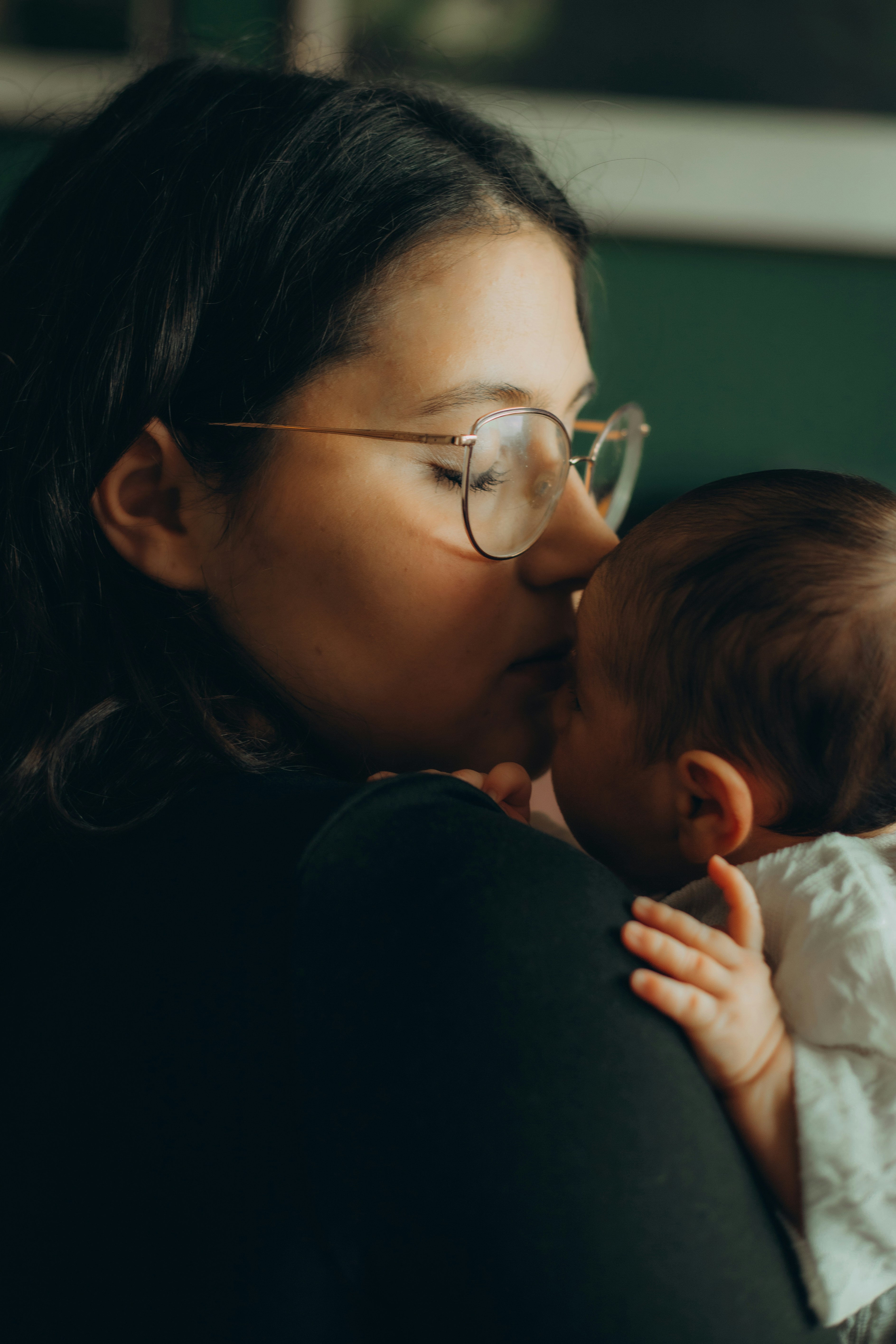 Woman holding and kissing a newborn baby.