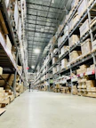 Tall shelves filled with cardboard boxes in a warehouse aisle.
