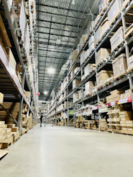 Tall shelves filled with cardboard boxes in a warehouse aisle.