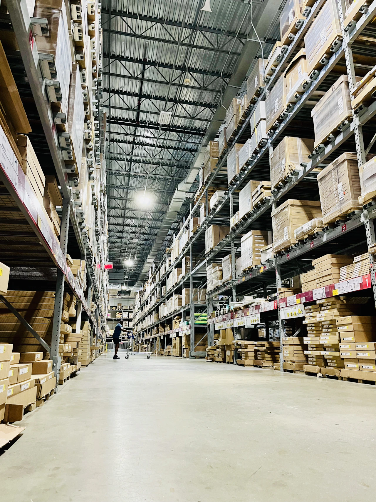 Tall warehouse shelving stacked with cartons, the package-level records a retail platform has to reconcile