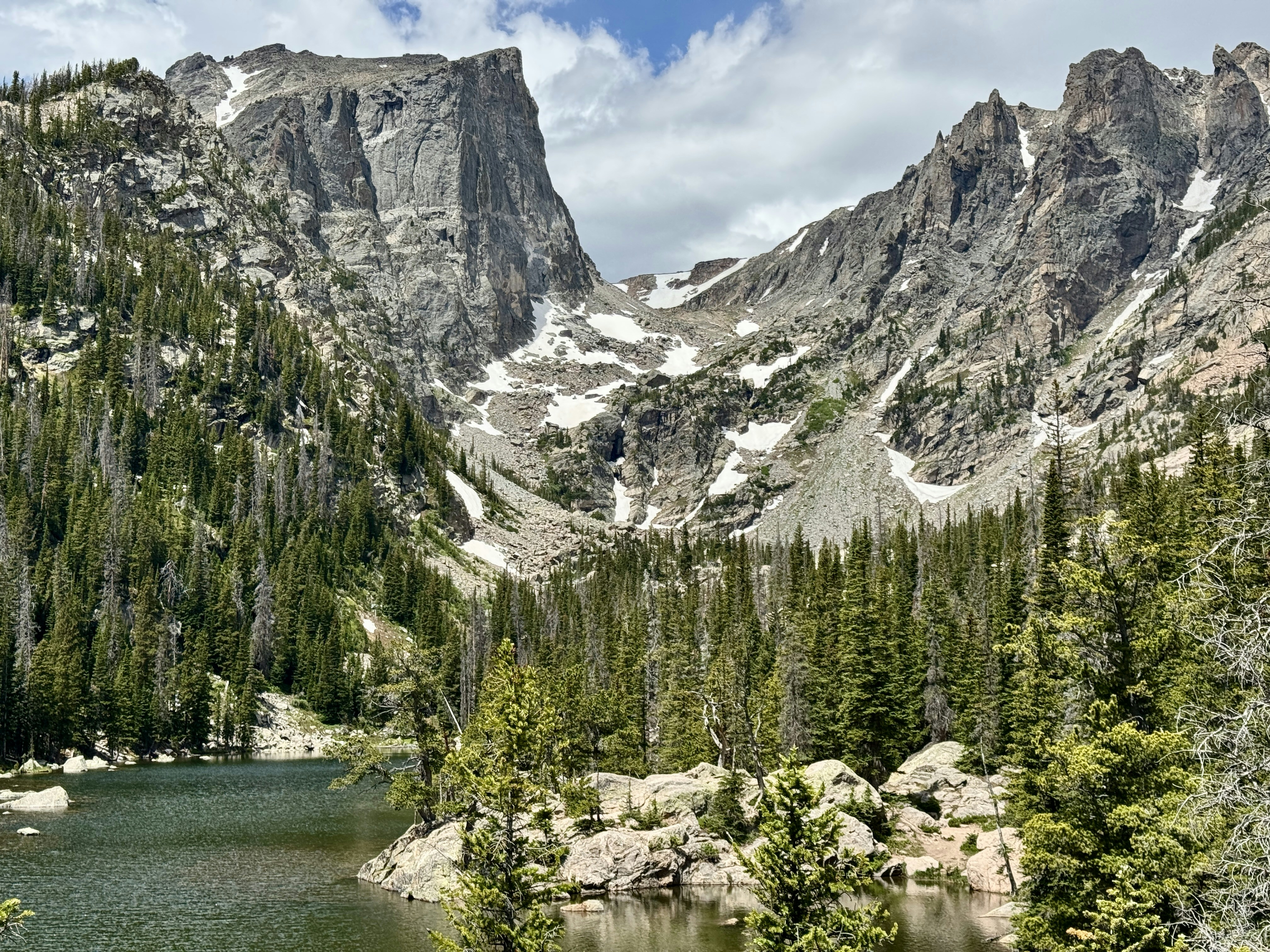 Majestic mountain lake surrounded by pine forests and snowy peaks.