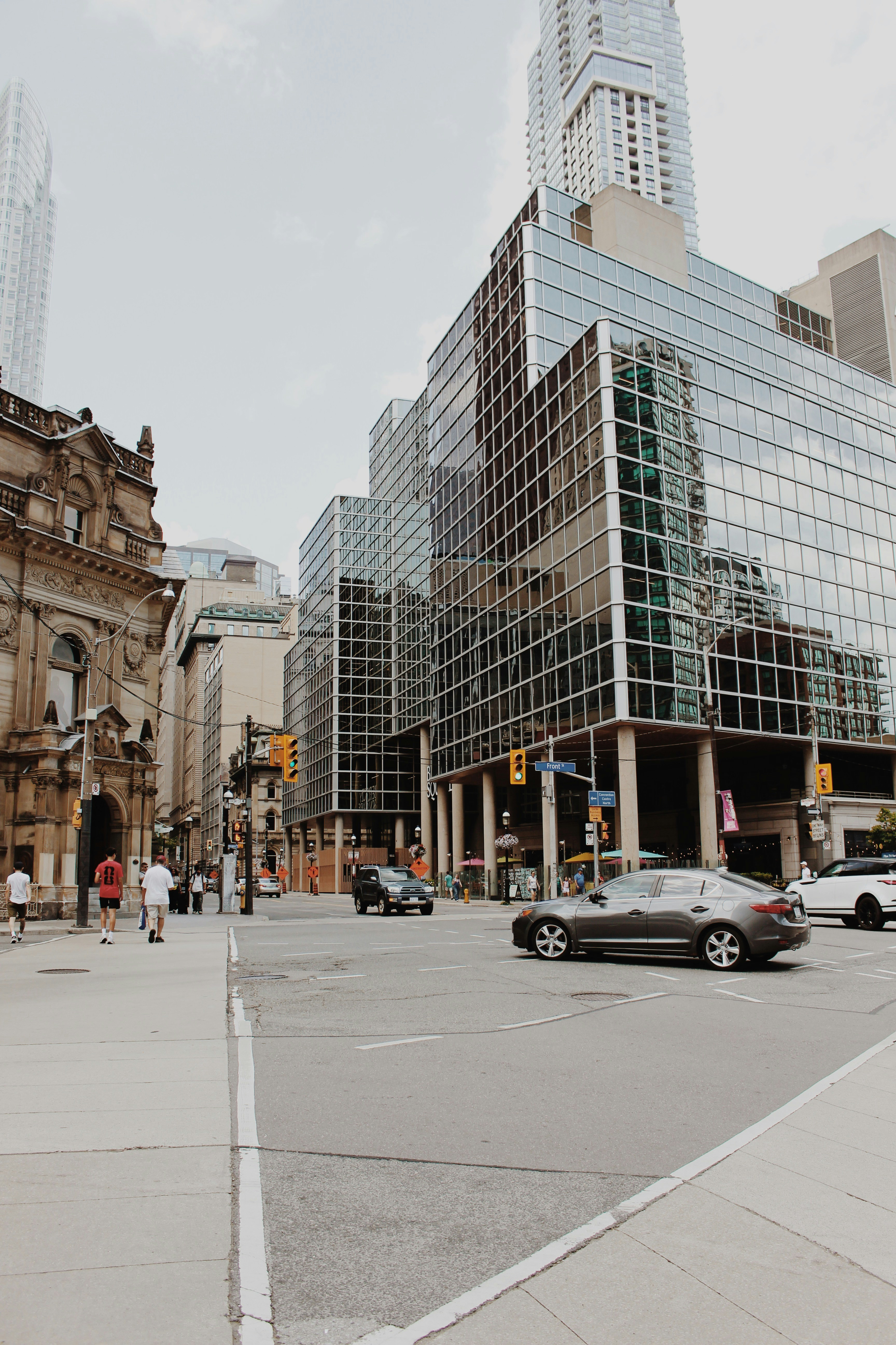 Urban intersection with glass buildings, cars, and people.