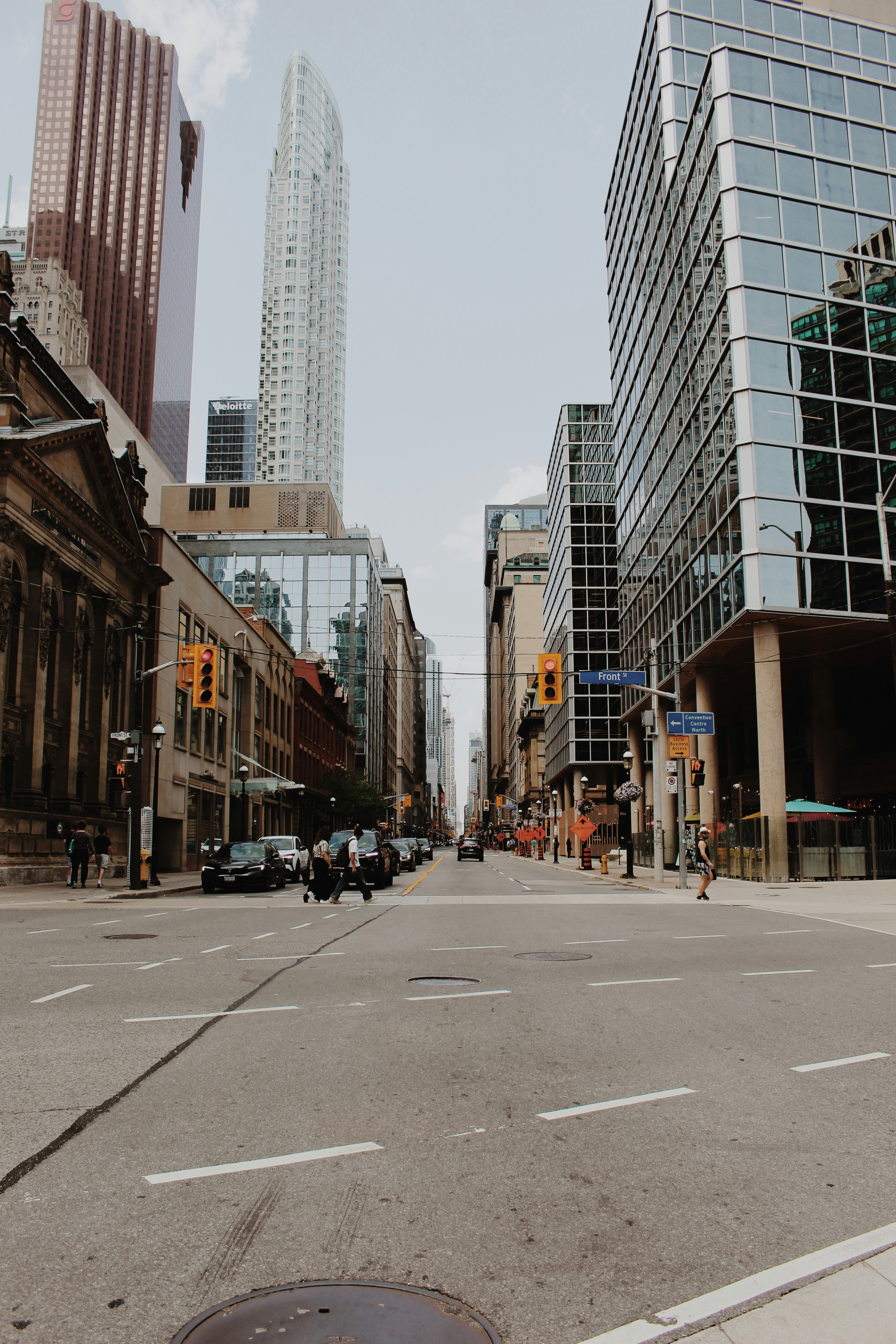 City street lined with tall buildings and traffic lights.