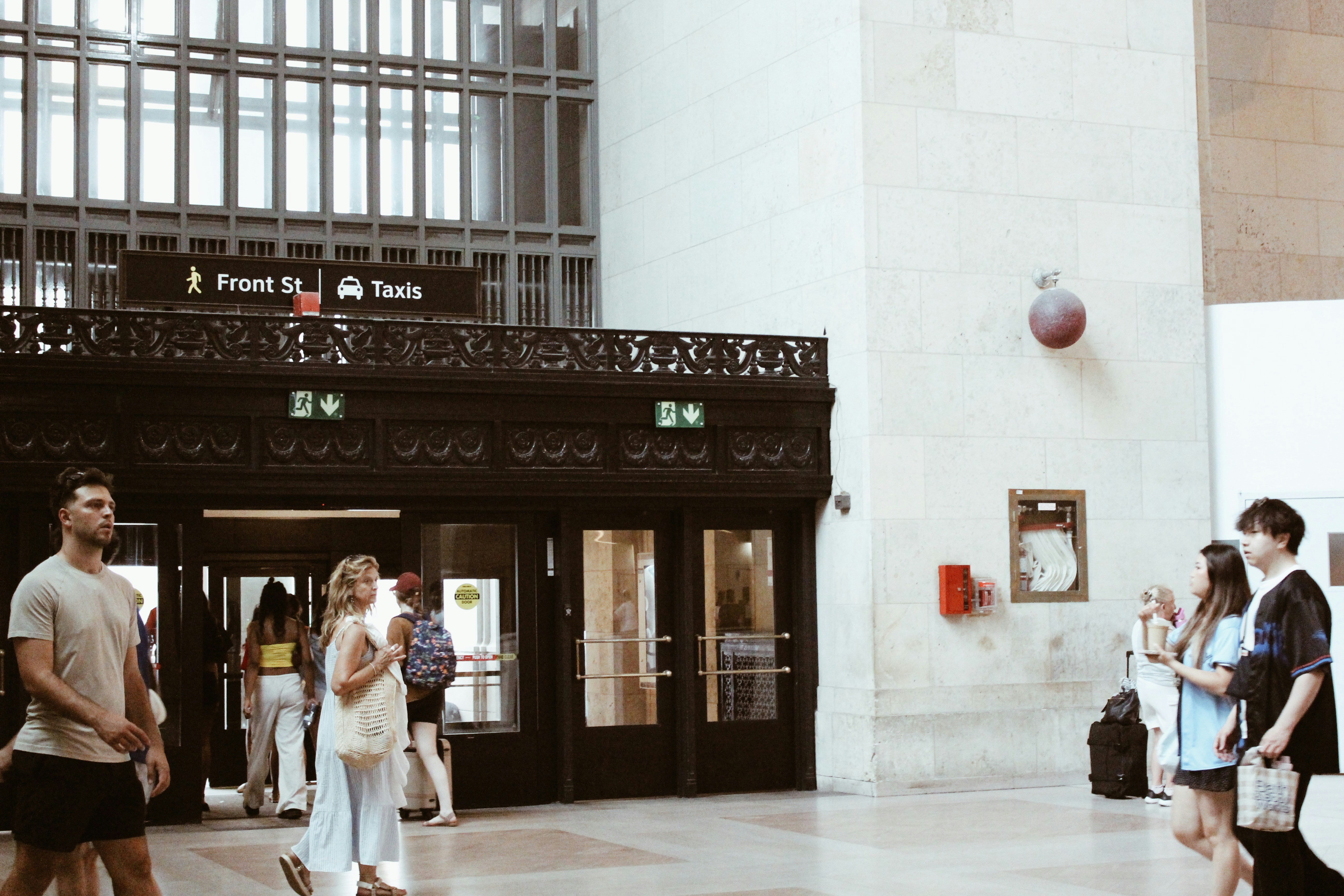 People walking through a grand train station entrance.