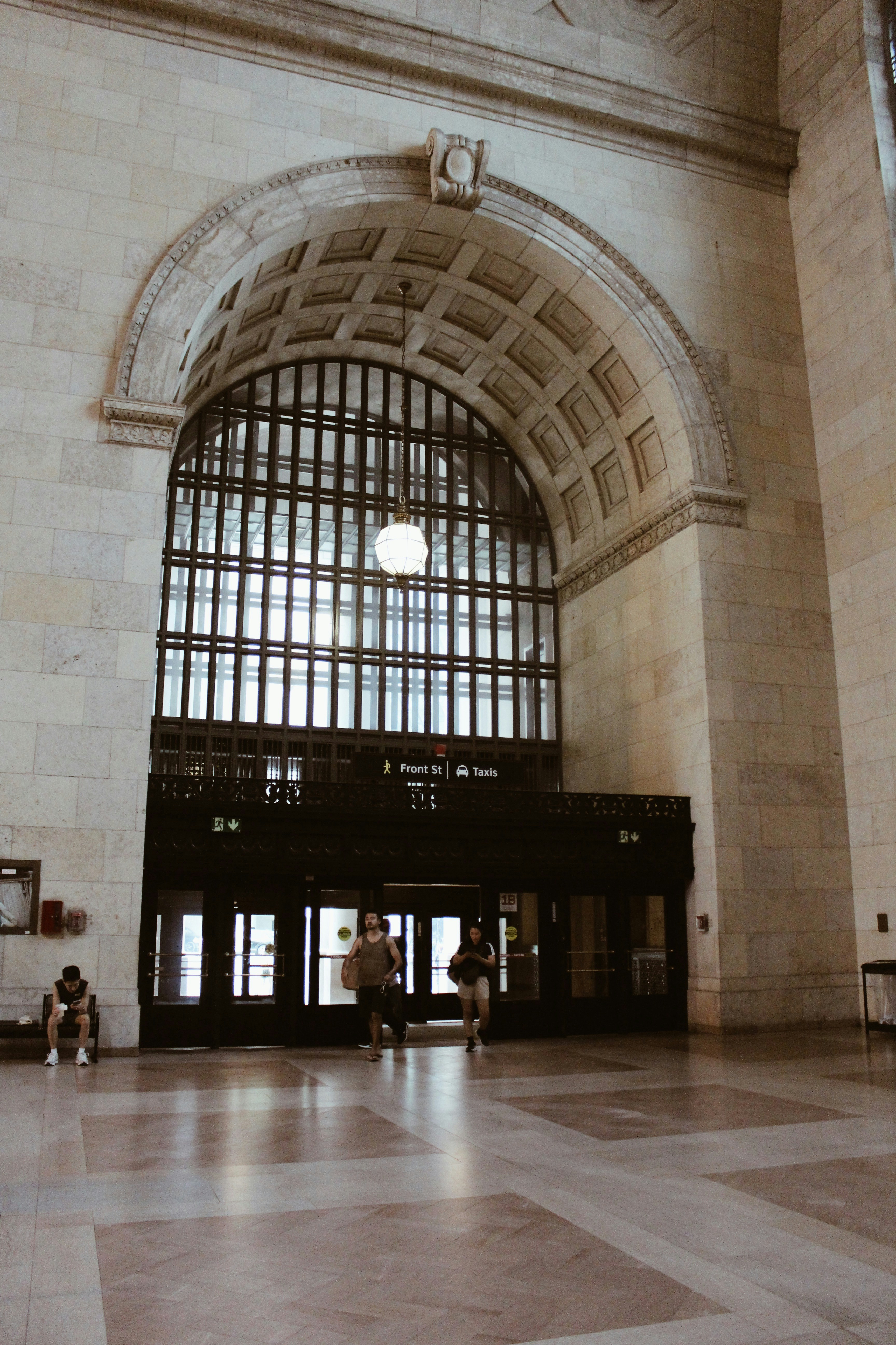 Grand arched entrance with people walking in a large hall.
